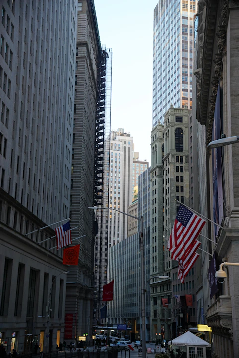 Tall buildings line a street with american flags.