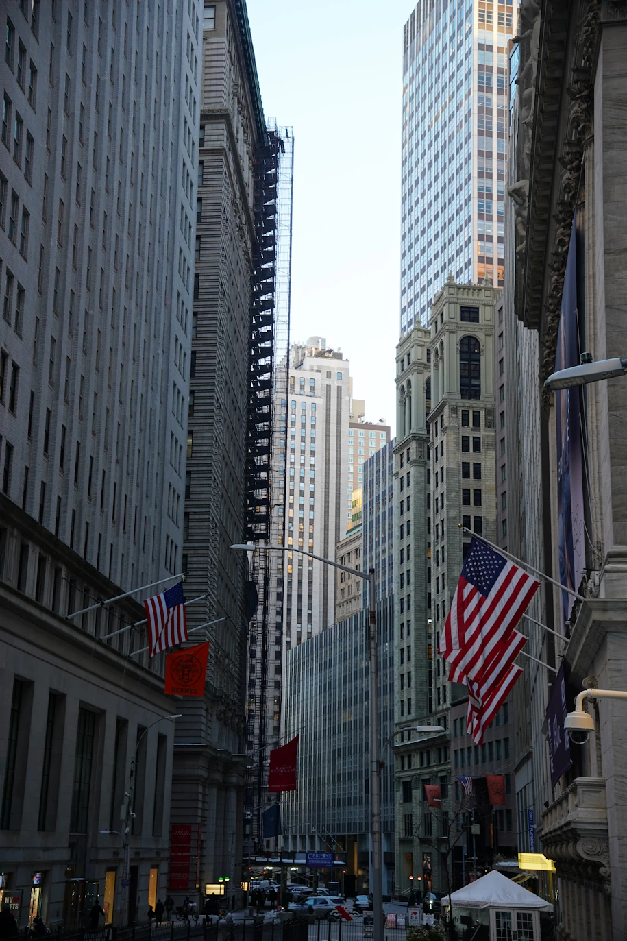 Tall buildings line a street with american flags.