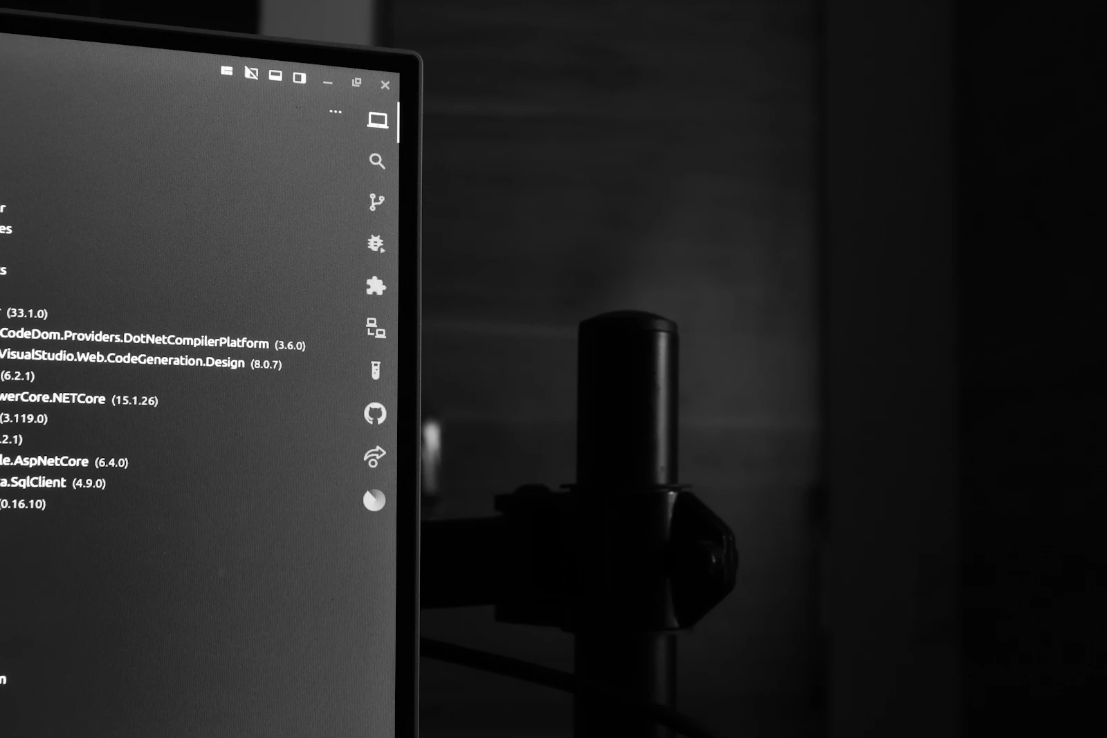 Großer Computermonitor zeigt farbige Codezeilen in einem dunklen, abgedunkelten Arbeitsraum