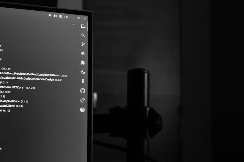 Großer Computermonitor zeigt farbige Codezeilen in einem dunklen, abgedunkelten Arbeitsraum