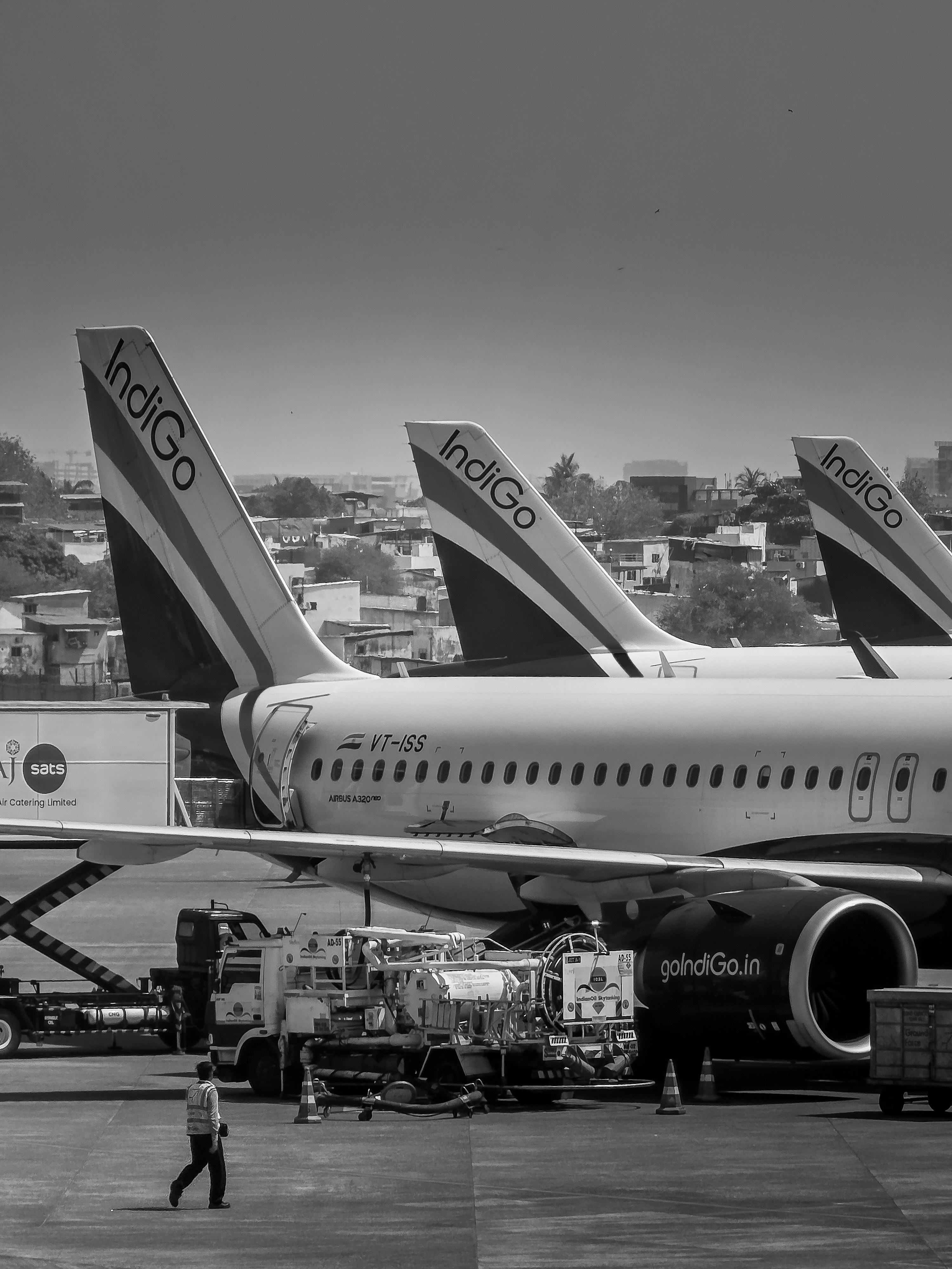 Three indigo airplanes parked on tarmac with ground crew.