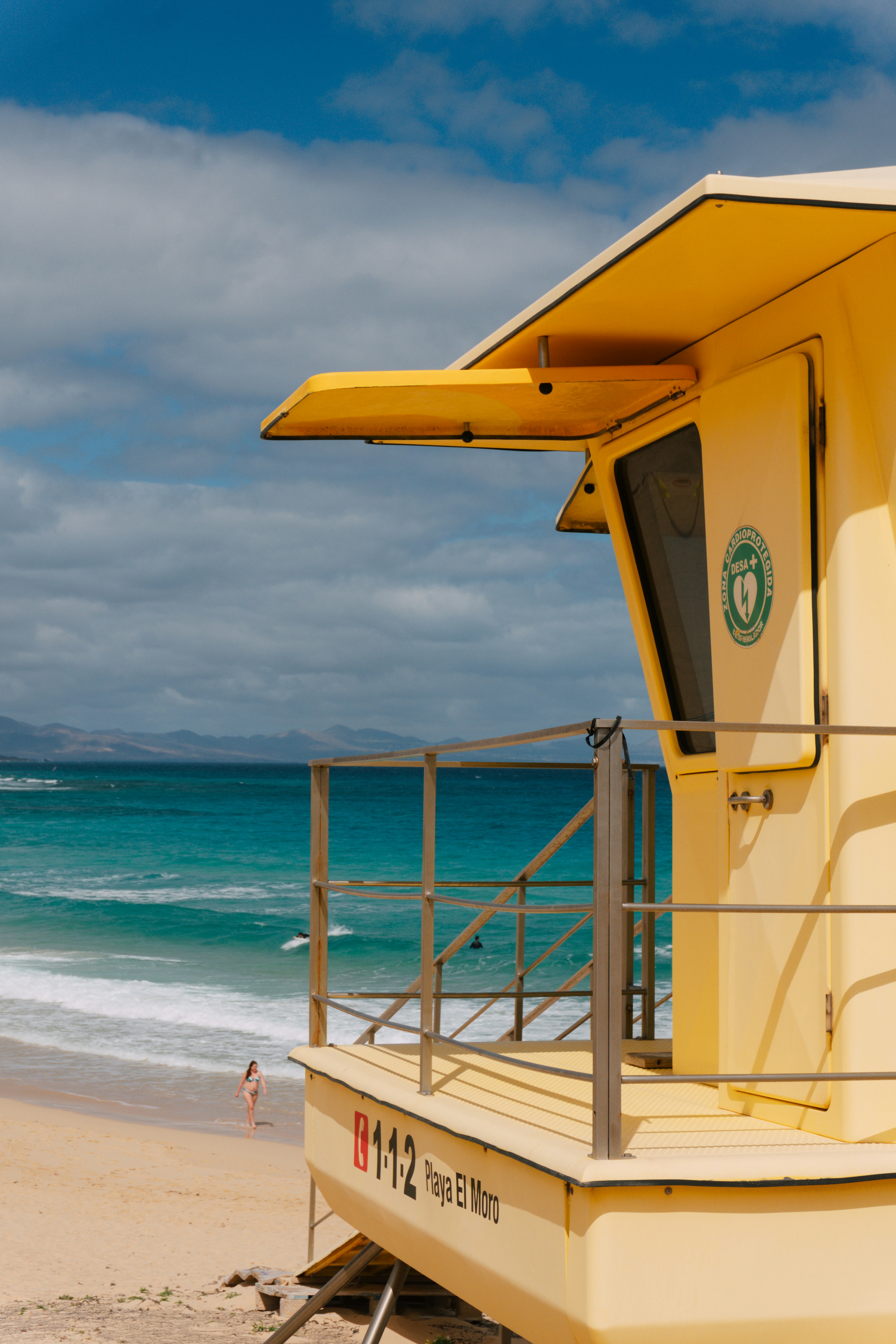 Yellow lifeguard station on a sandy beach with ocean waves.