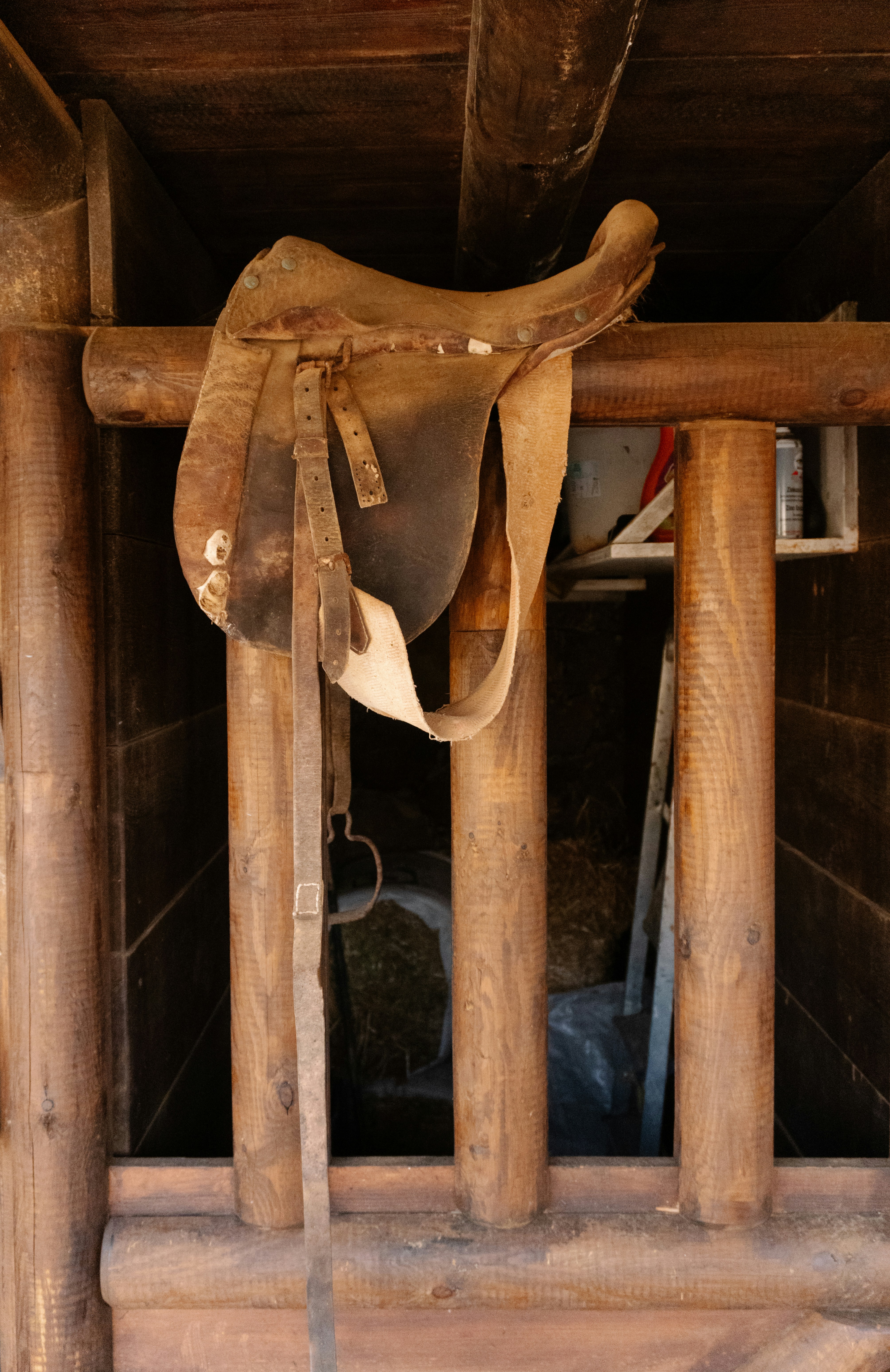Old leather saddle hanging on wooden beams