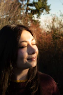 A young woman with eyes closed in sunlight