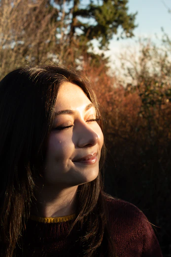 A young woman with eyes closed in sunlight