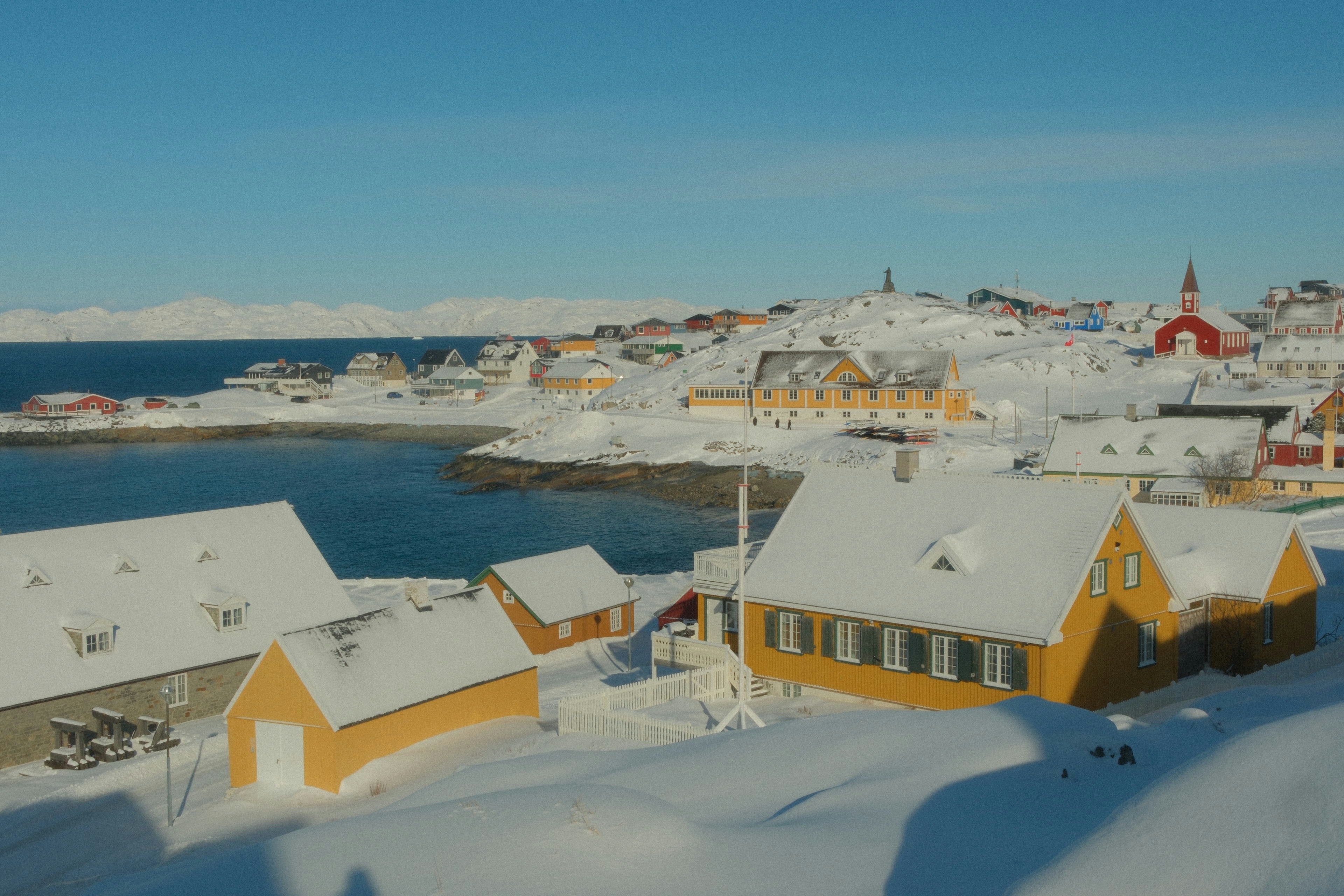 Vila coberta de neve à beira do oceano com montanhas