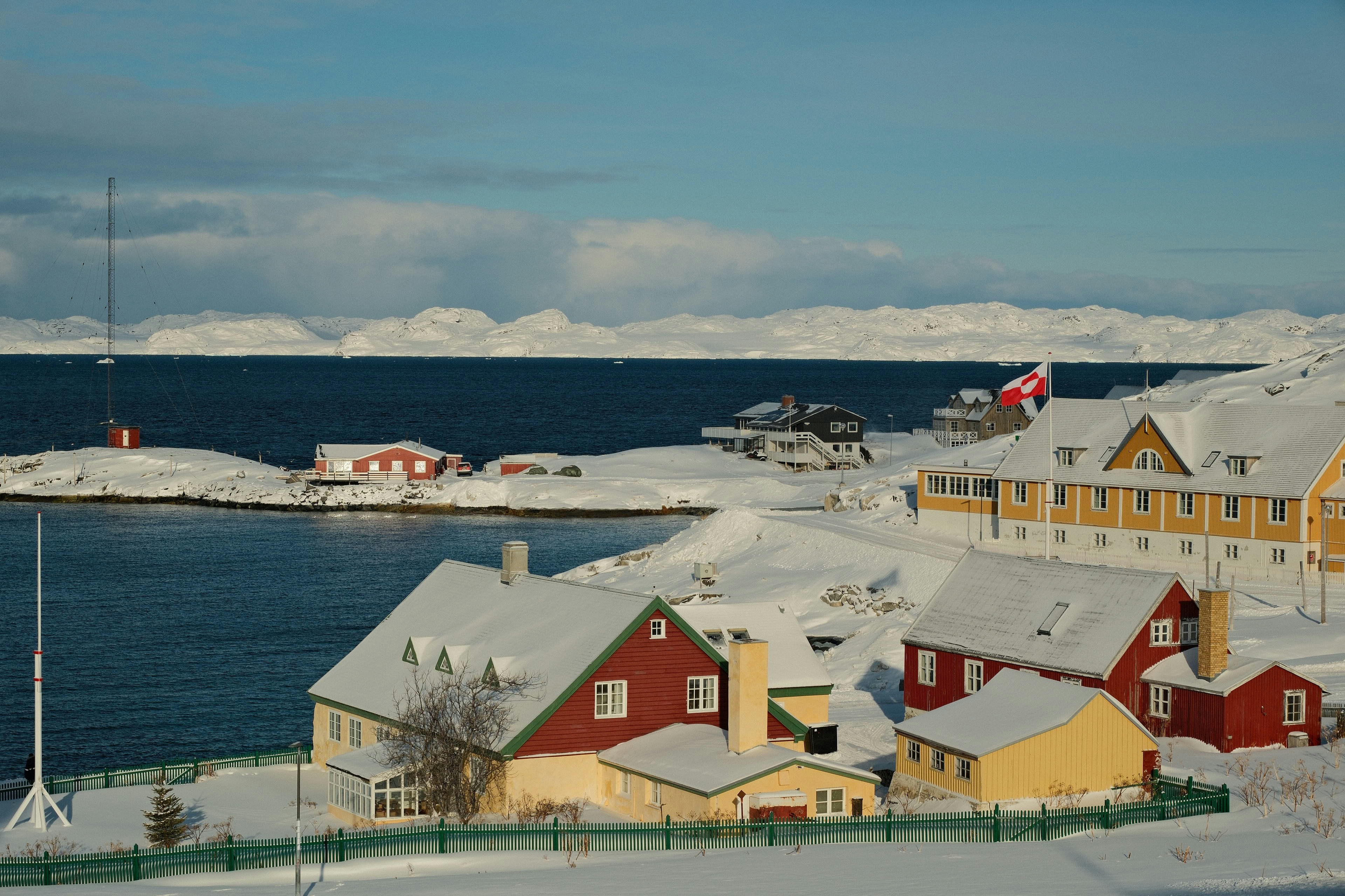 Vila coberta de neve à beira de uma baía azul calma