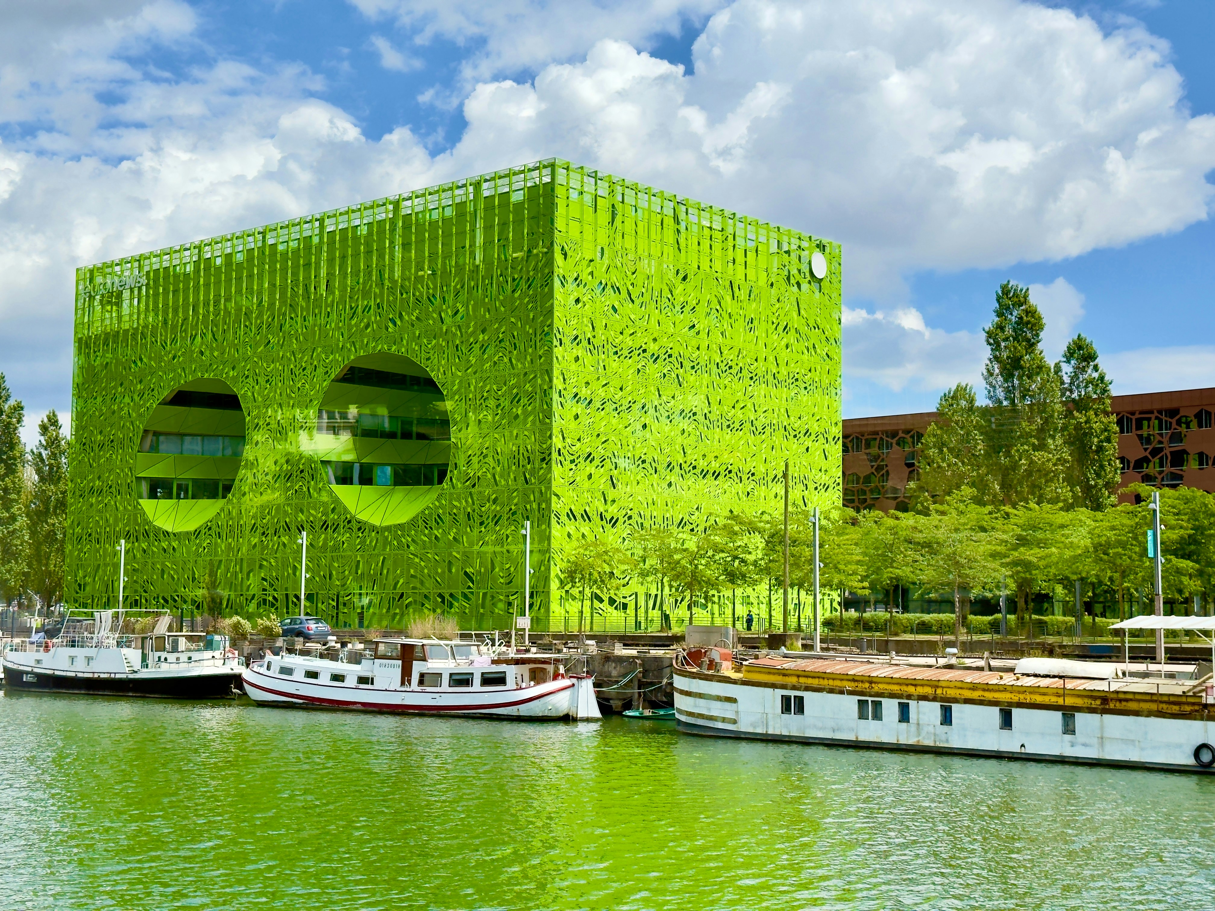 A vibrant green building covered in plants by the water