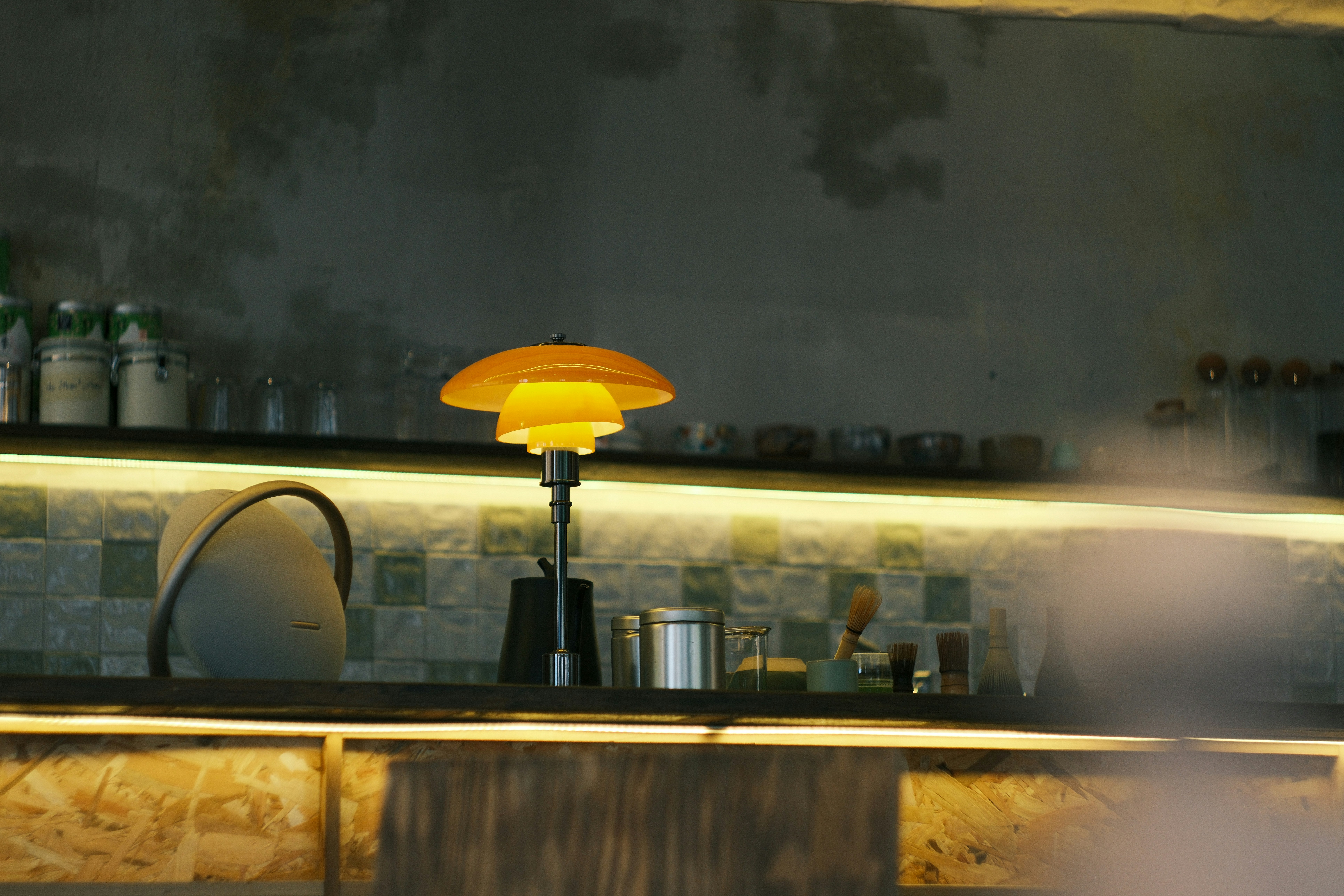 A retro lamp sits on a shelf behind-the-bar shelf.