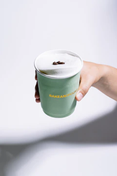 Hand holding a green cup with foamy drink