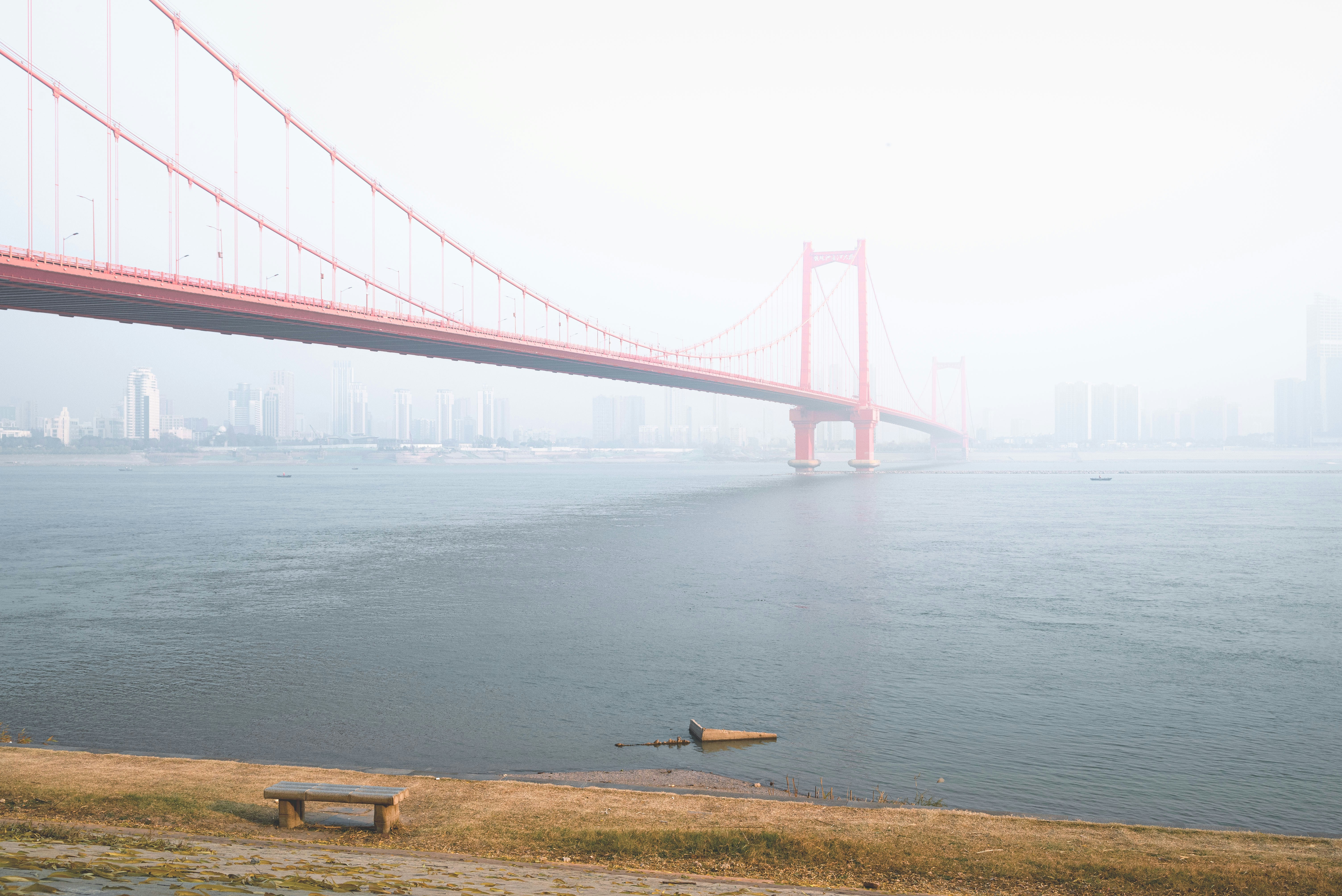 Rote Hängebrücke über einen nebligen Fluss