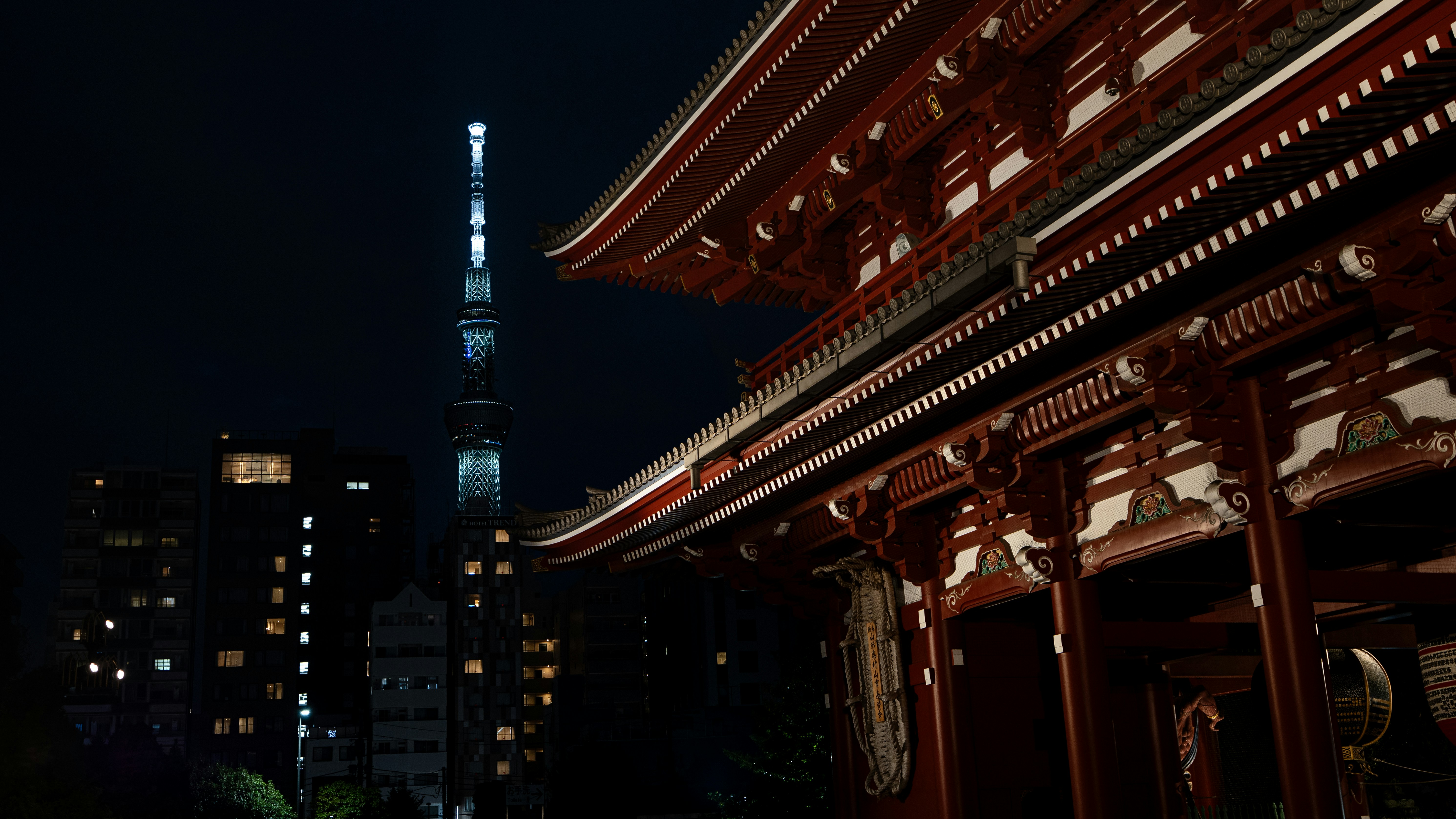 Traditional japanese temple at night with modern skyscraper