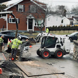 Workers use a skid steer loader for construction work