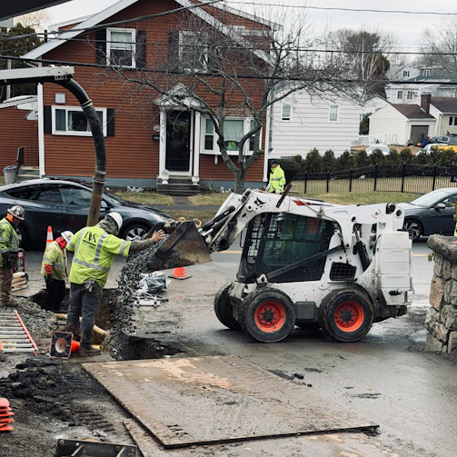 Workers use a skid steer loader for construction work