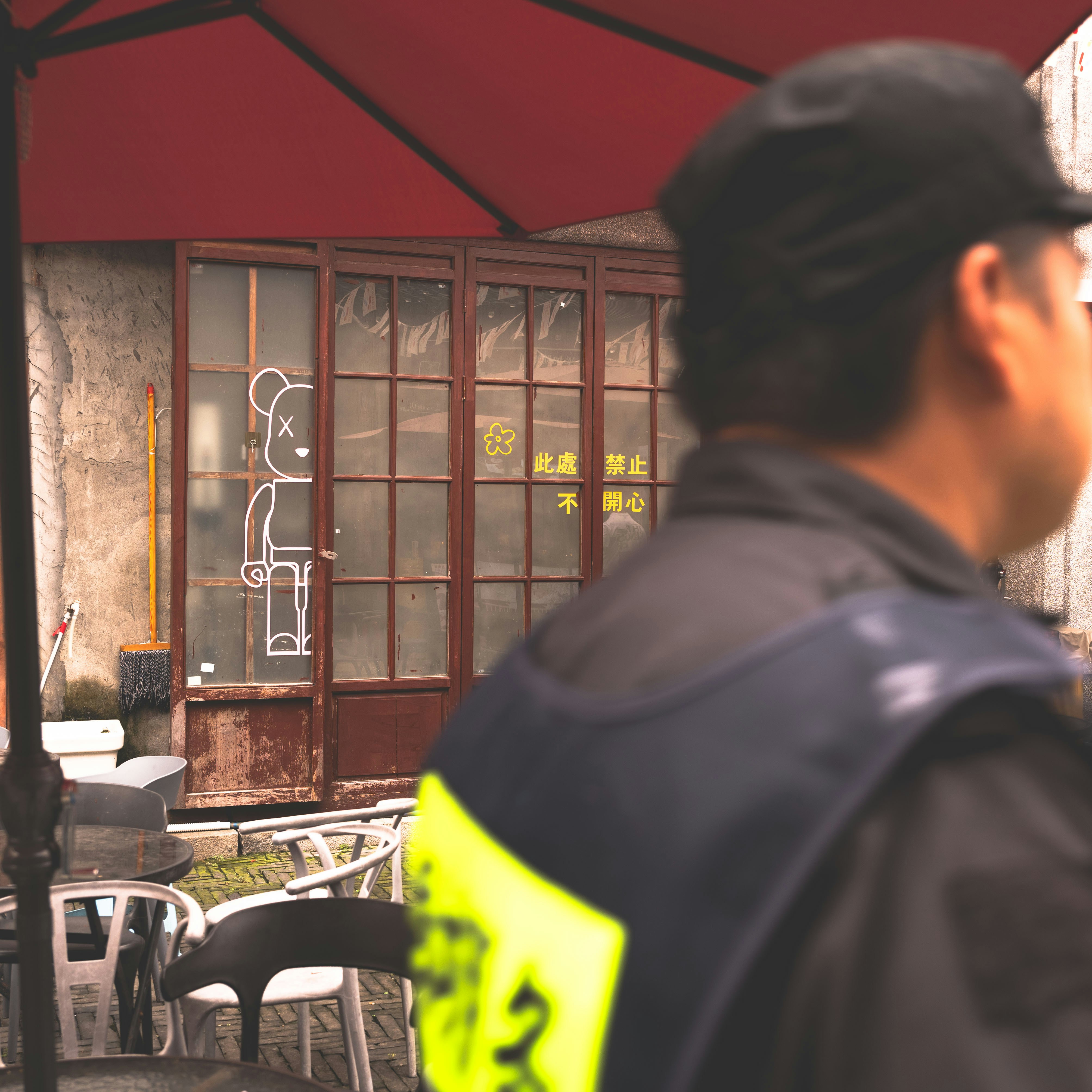 vigilance: A person in a dark uniform with a yellow vest near a cafe terrace
