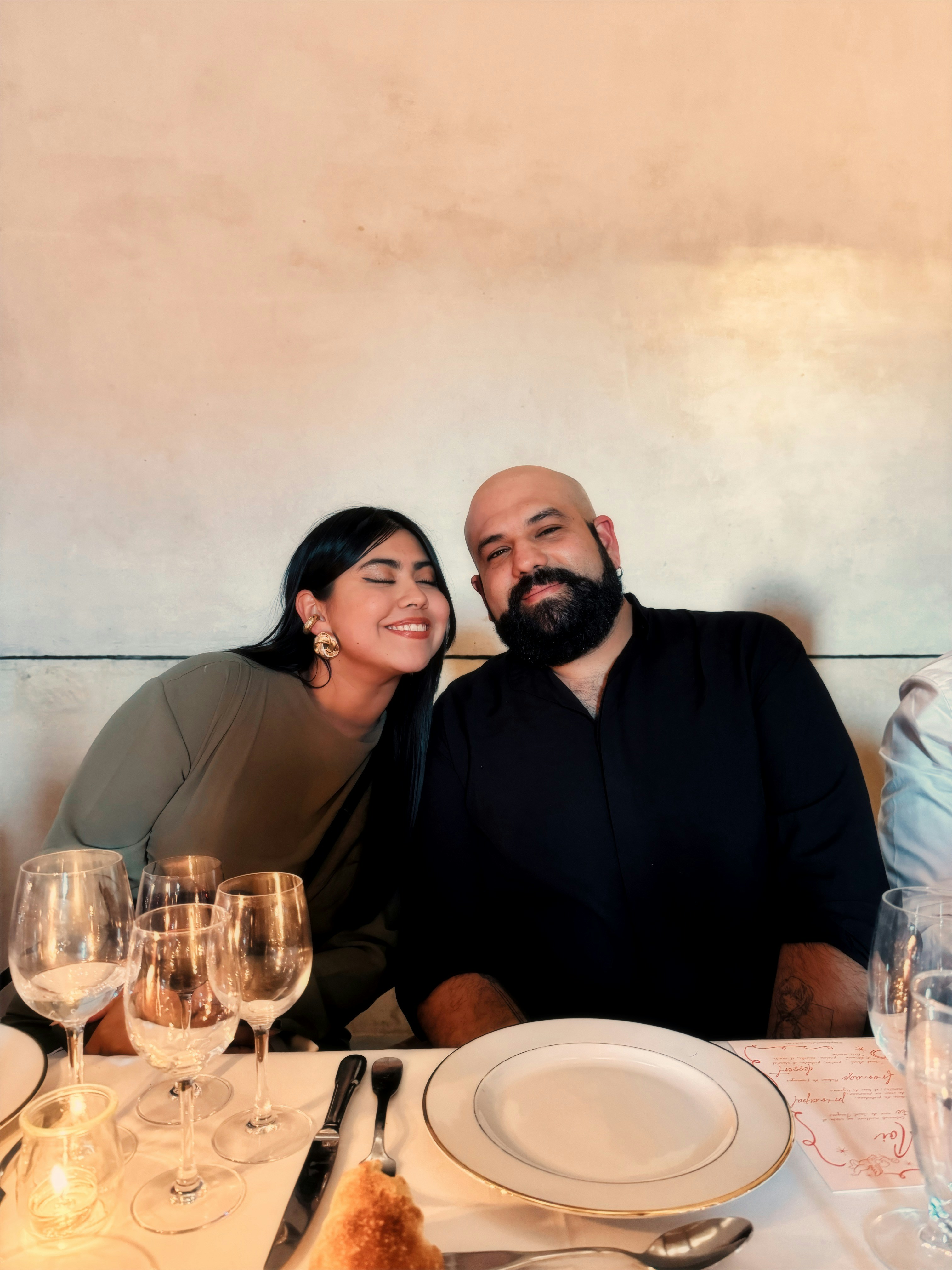 A couple smiles while sitting at a restaurant table