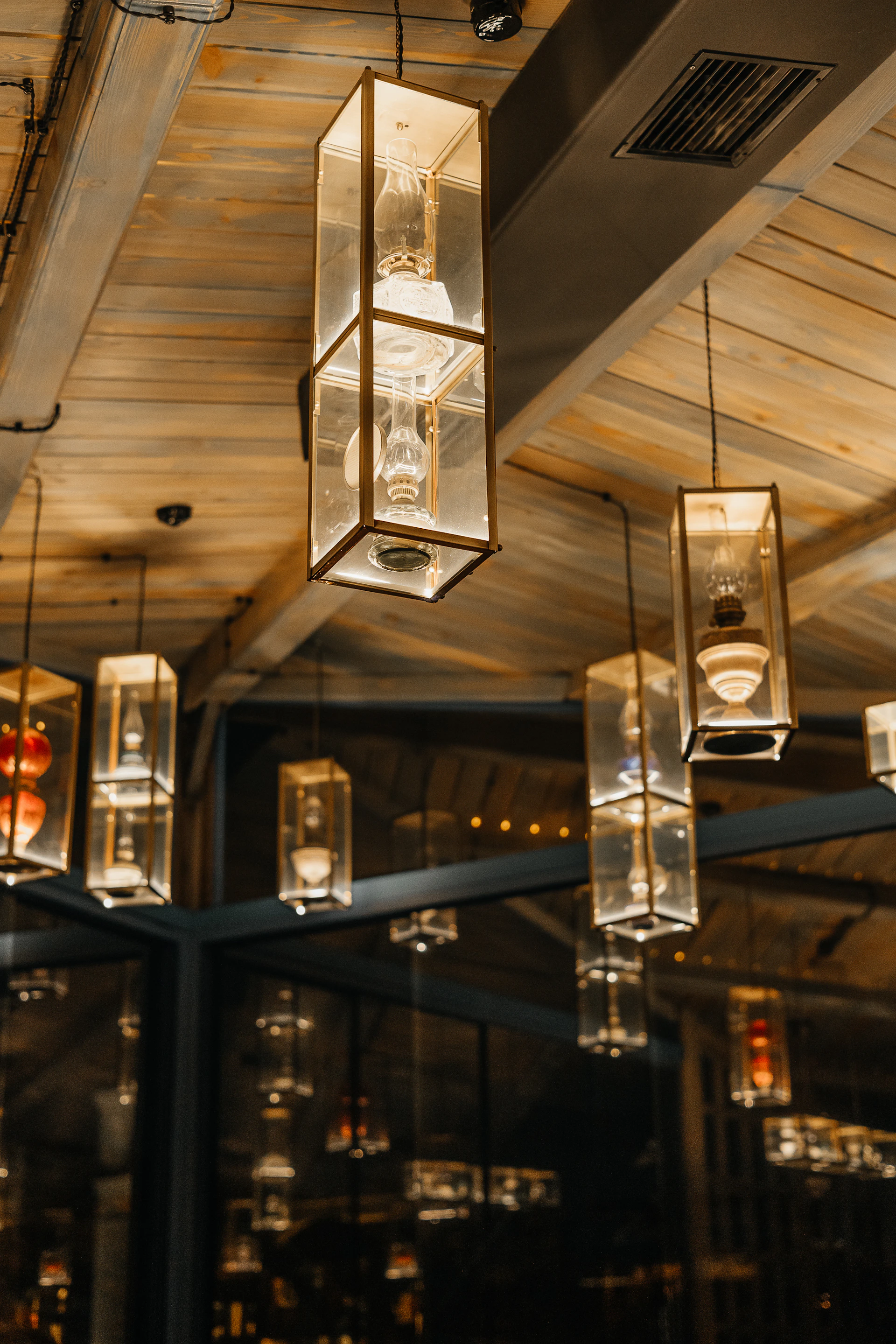 Hanging glass lanterns illuminate a wooden ceiling