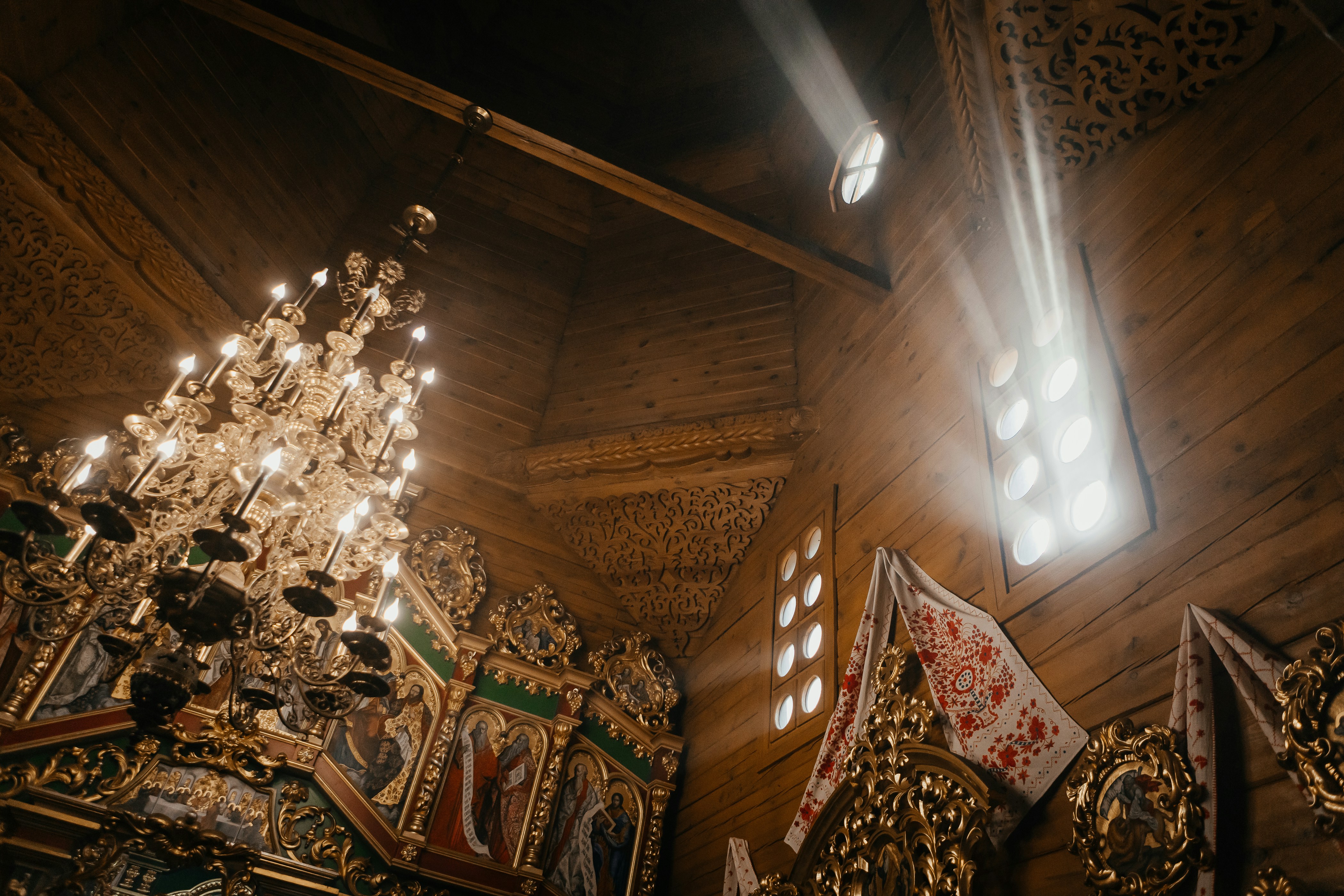 A luz do sol entra por uma janela em uma igreja de madeira.