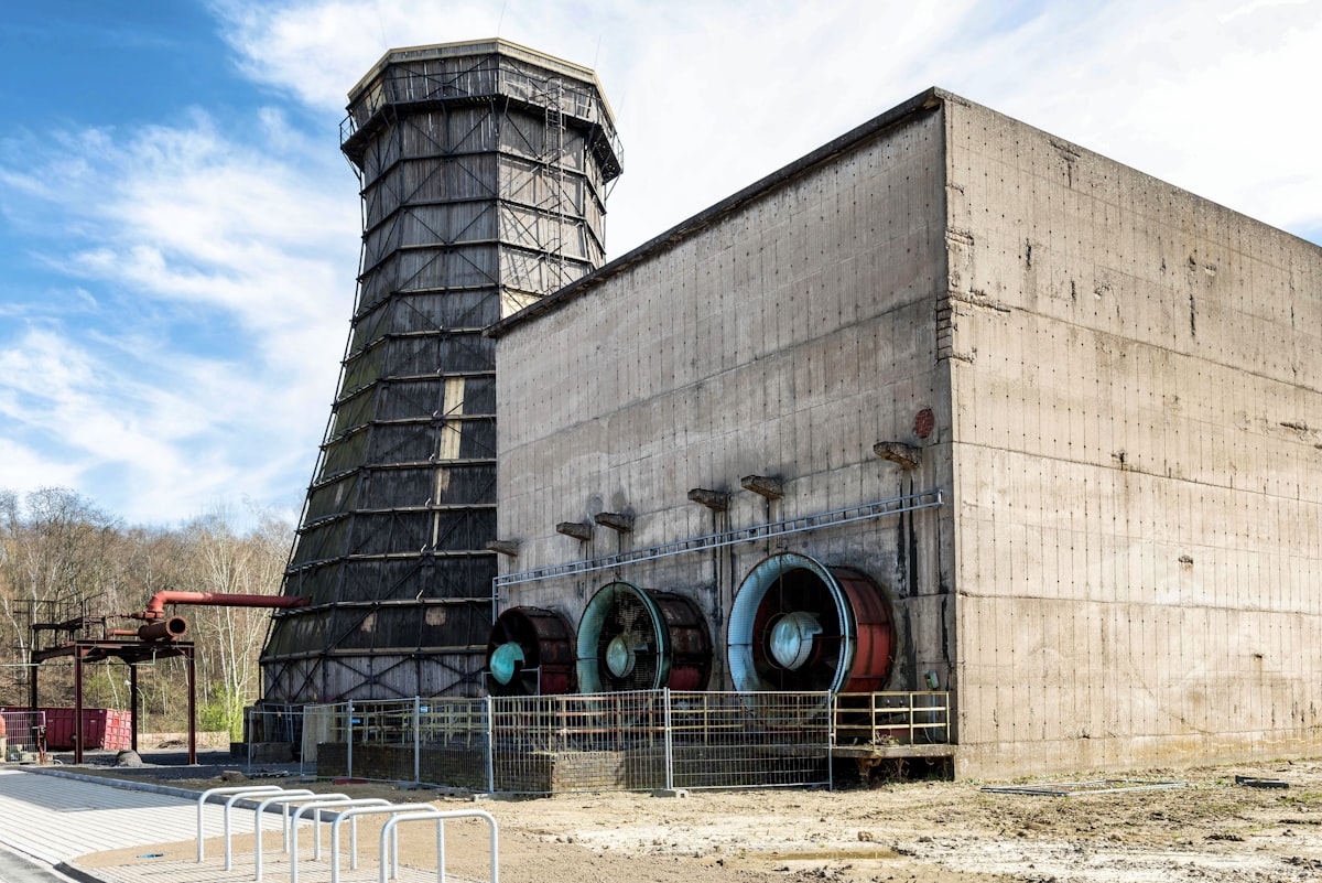 Industrial mechanical-draft cooling tower with large ventilation fans mounted on a concrete building — typical induced-draft installation handling rejected heat from process or HVAC chiller systems. Photo: Wolfgang Weiser / Unsplash