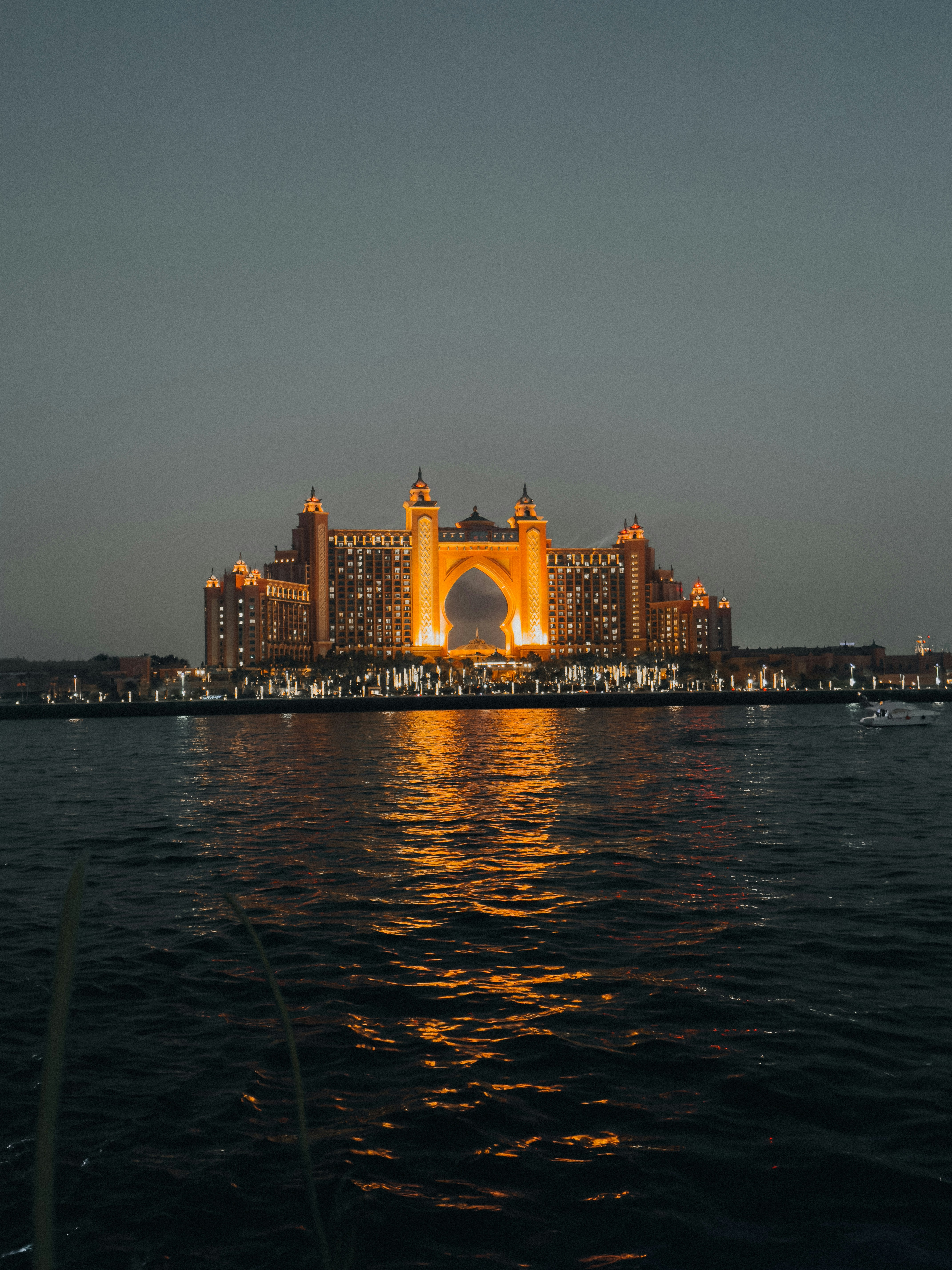 Grand hotel building illuminated at dusk with water reflection