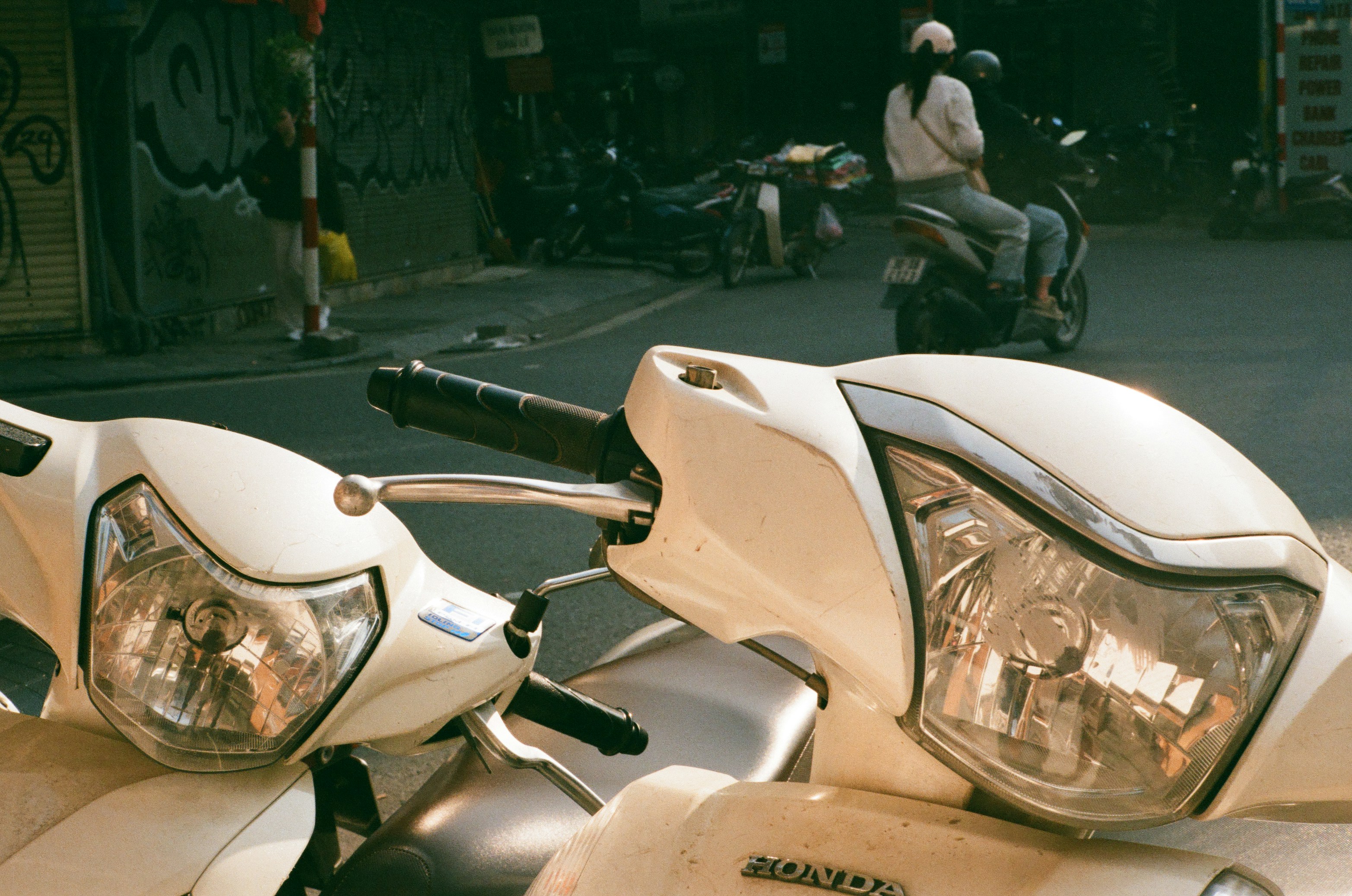 Two white scooters parked on a street.
