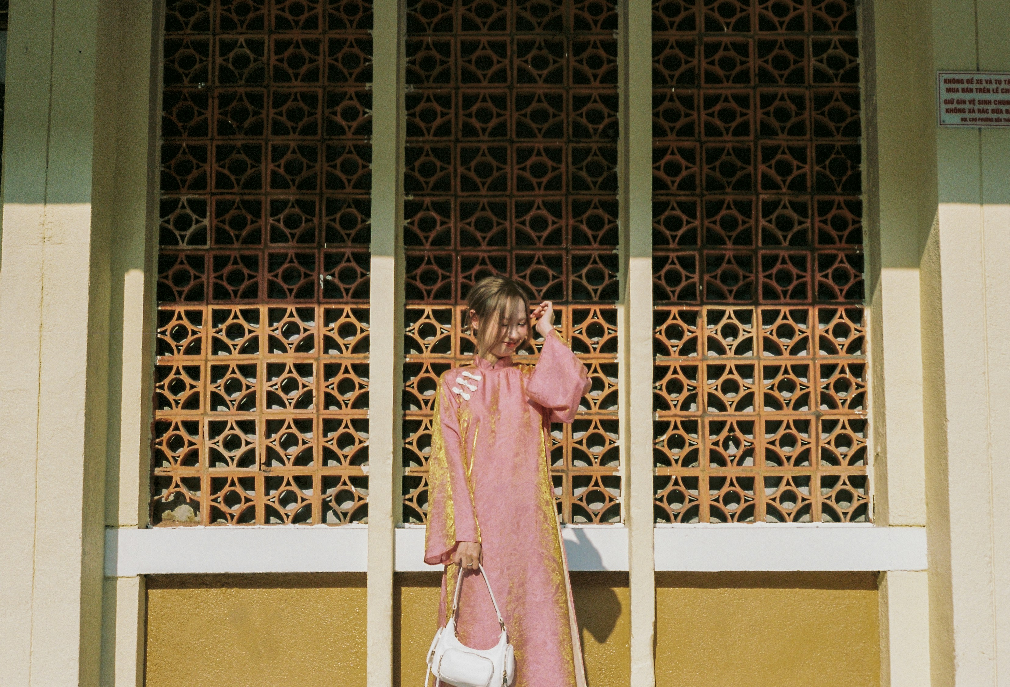 A woman in a pink dress holding a white purse.