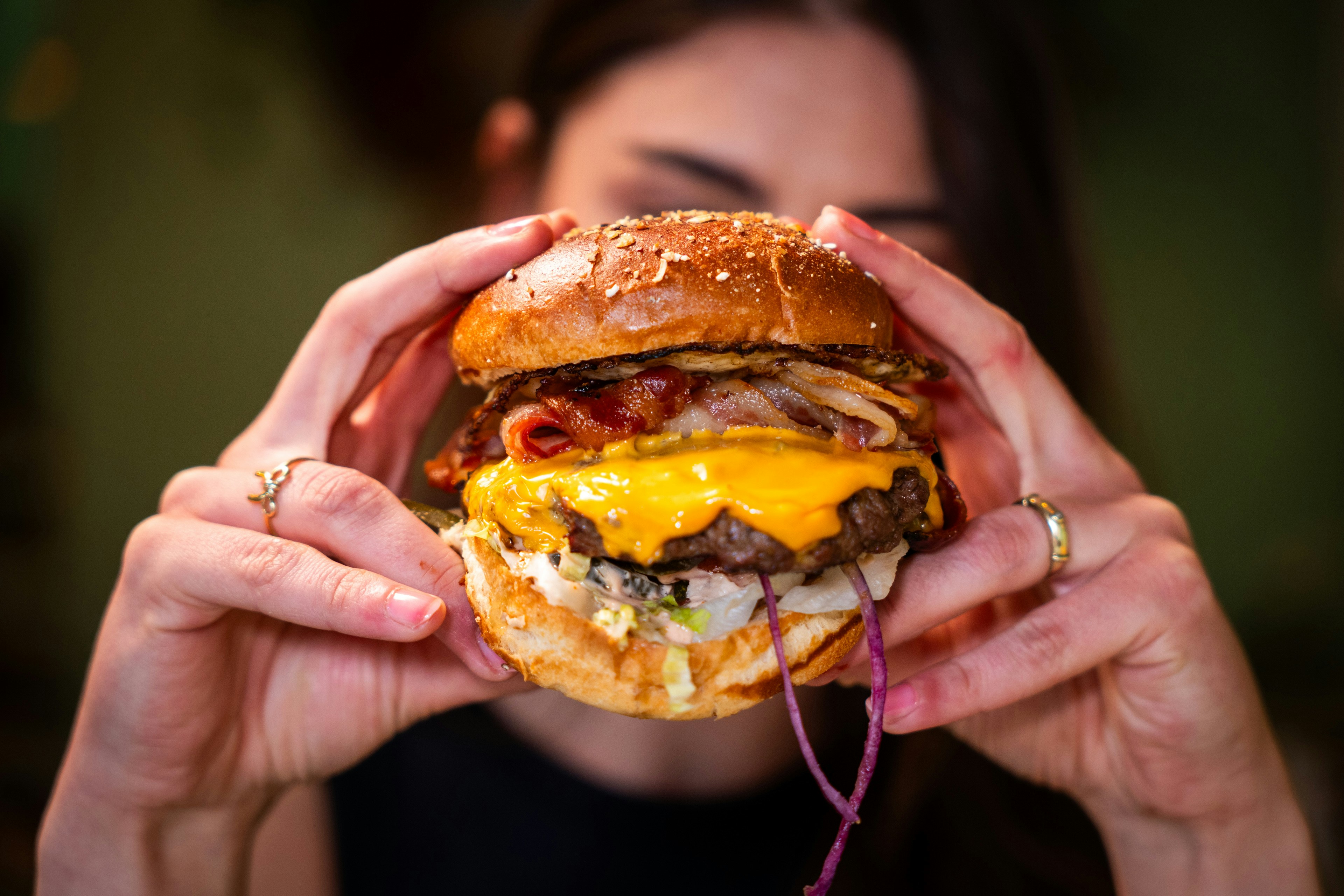 Person holding a large cheeseburger with both hands