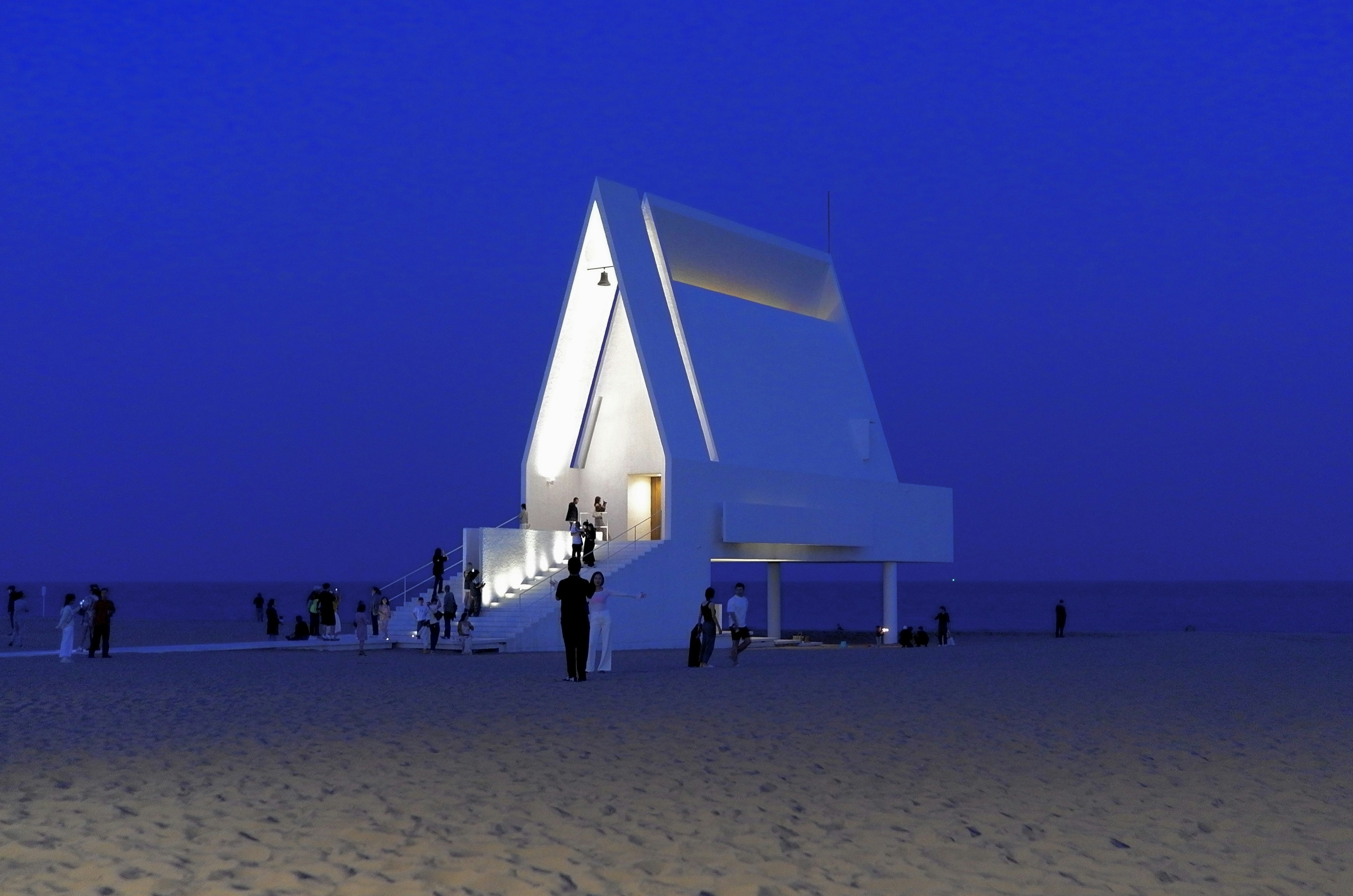 Modern white building on a sandy beach at night.