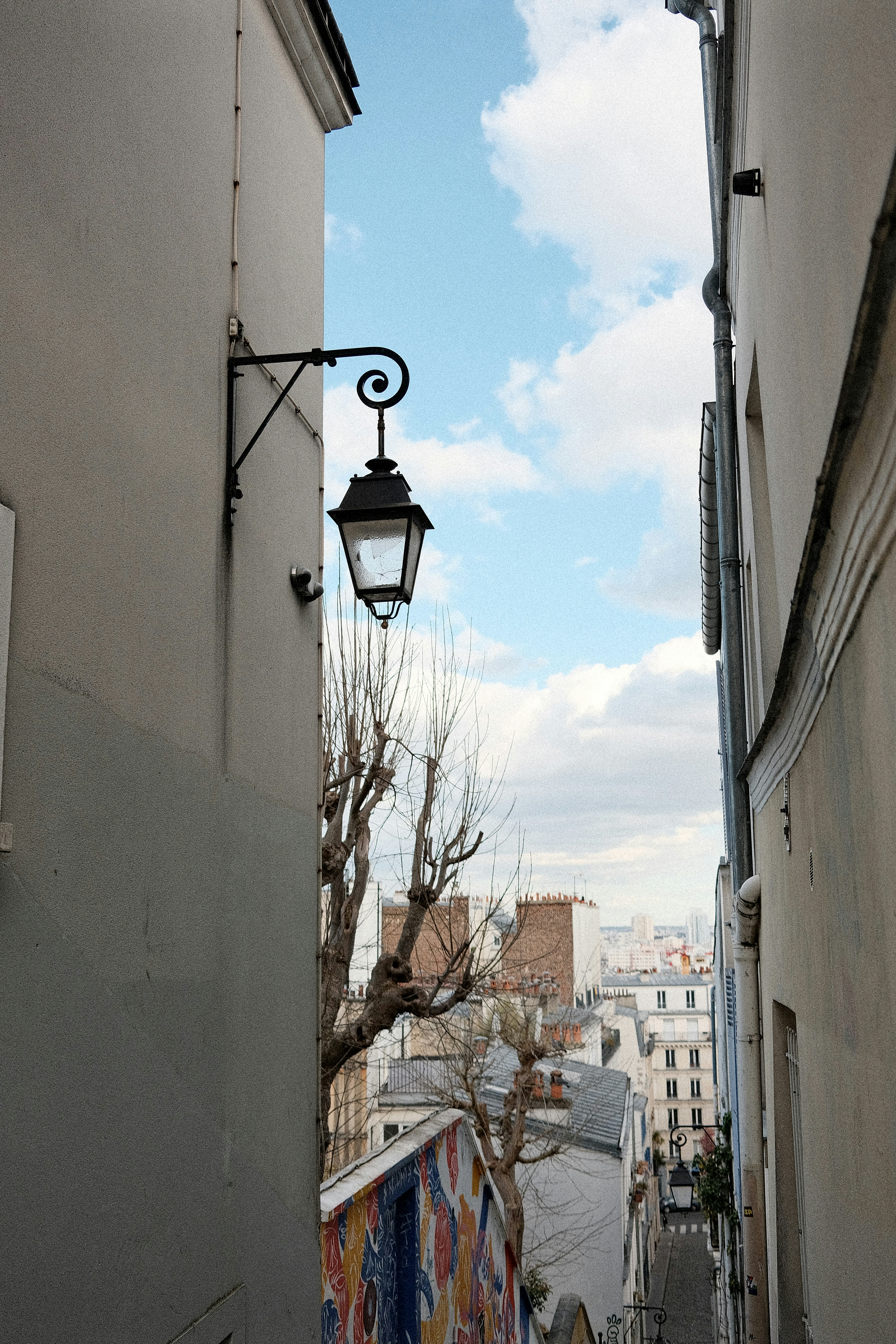 Luminária ornamentada em um beco estreito com prédios.