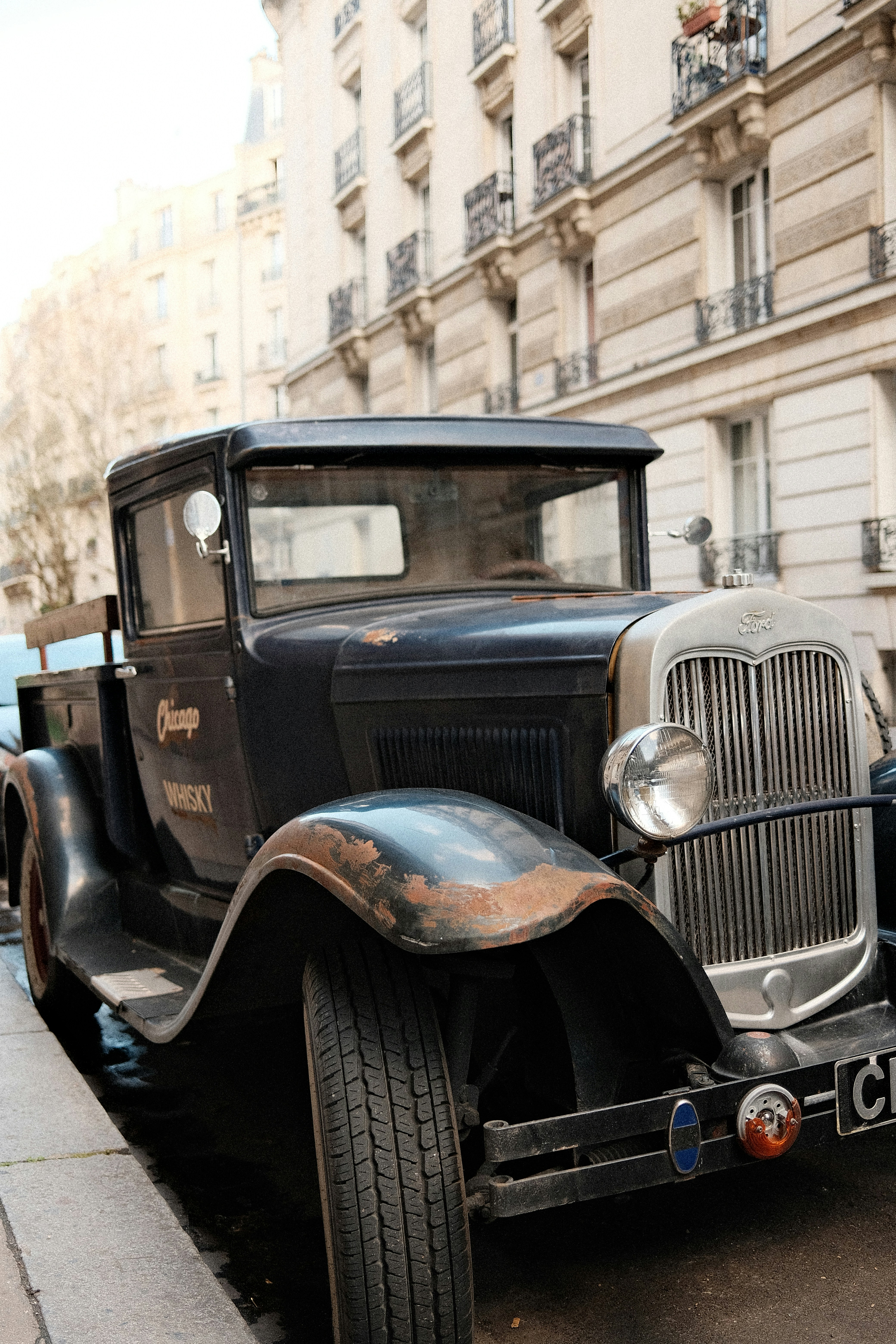 Caminhão preto antigo estacionado numa rua da cidade.