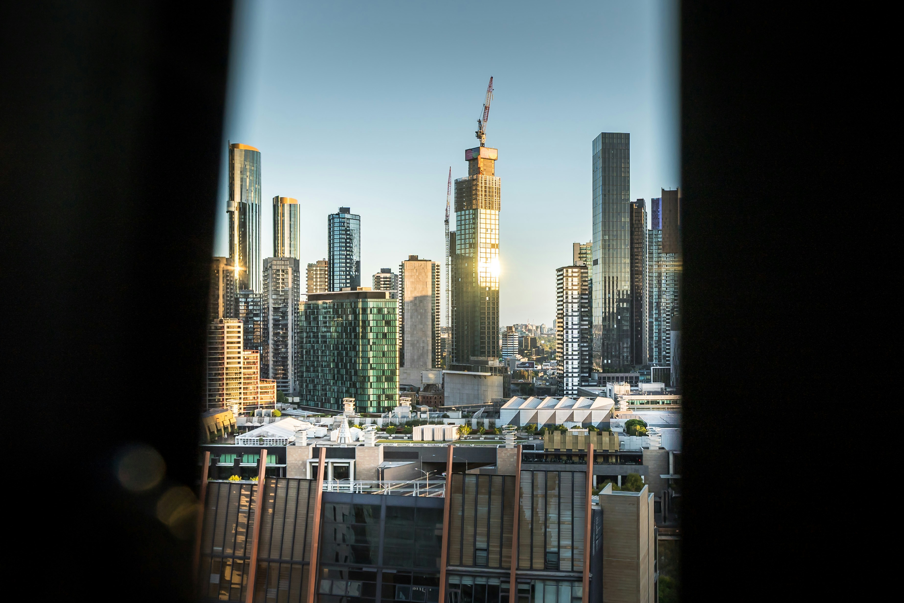 Modern cityscape with skyscrapers and construction at sunset.