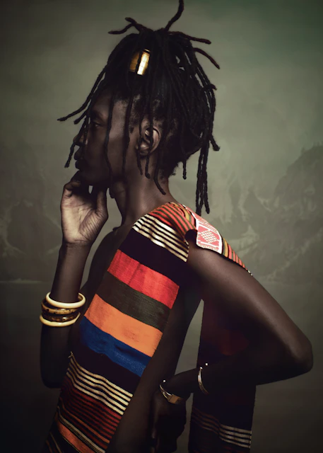 Person with dreadlocks wearing colorful striped clothing.