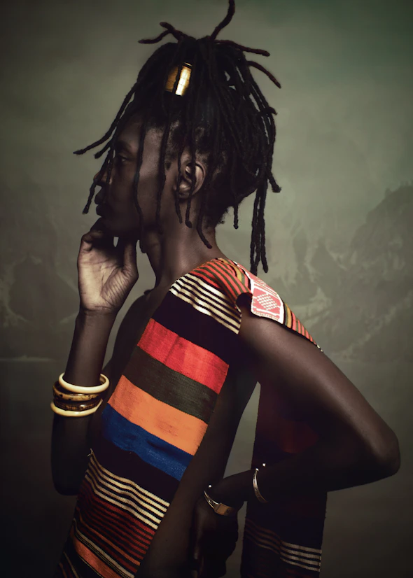 Person with dreadlocks wearing colorful striped clothing.