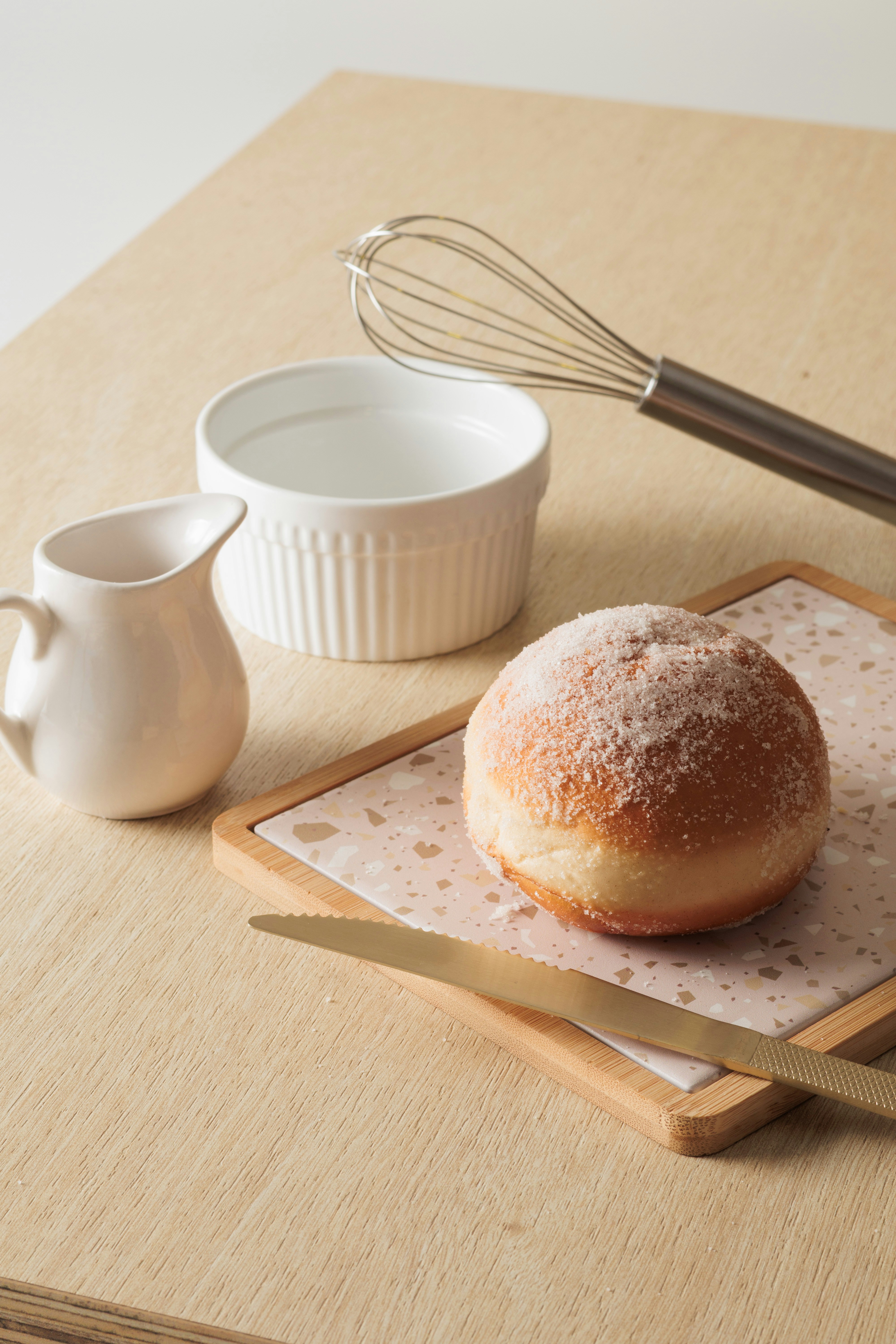 A sugar-dusted pastry with baking utensils on a wooden surface.
