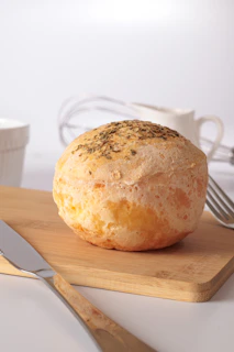 A round bread roll with herbs on a wooden board.