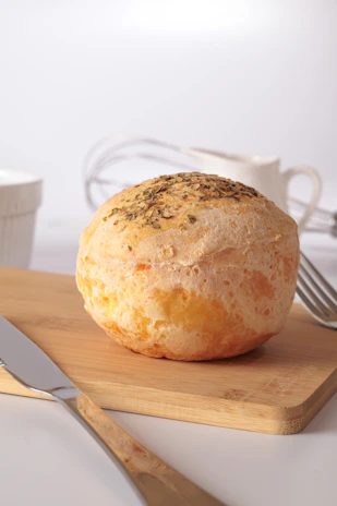 A round bread roll with herbs on a wooden board.
