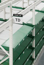 Empty green shelves in a warehouse with signs