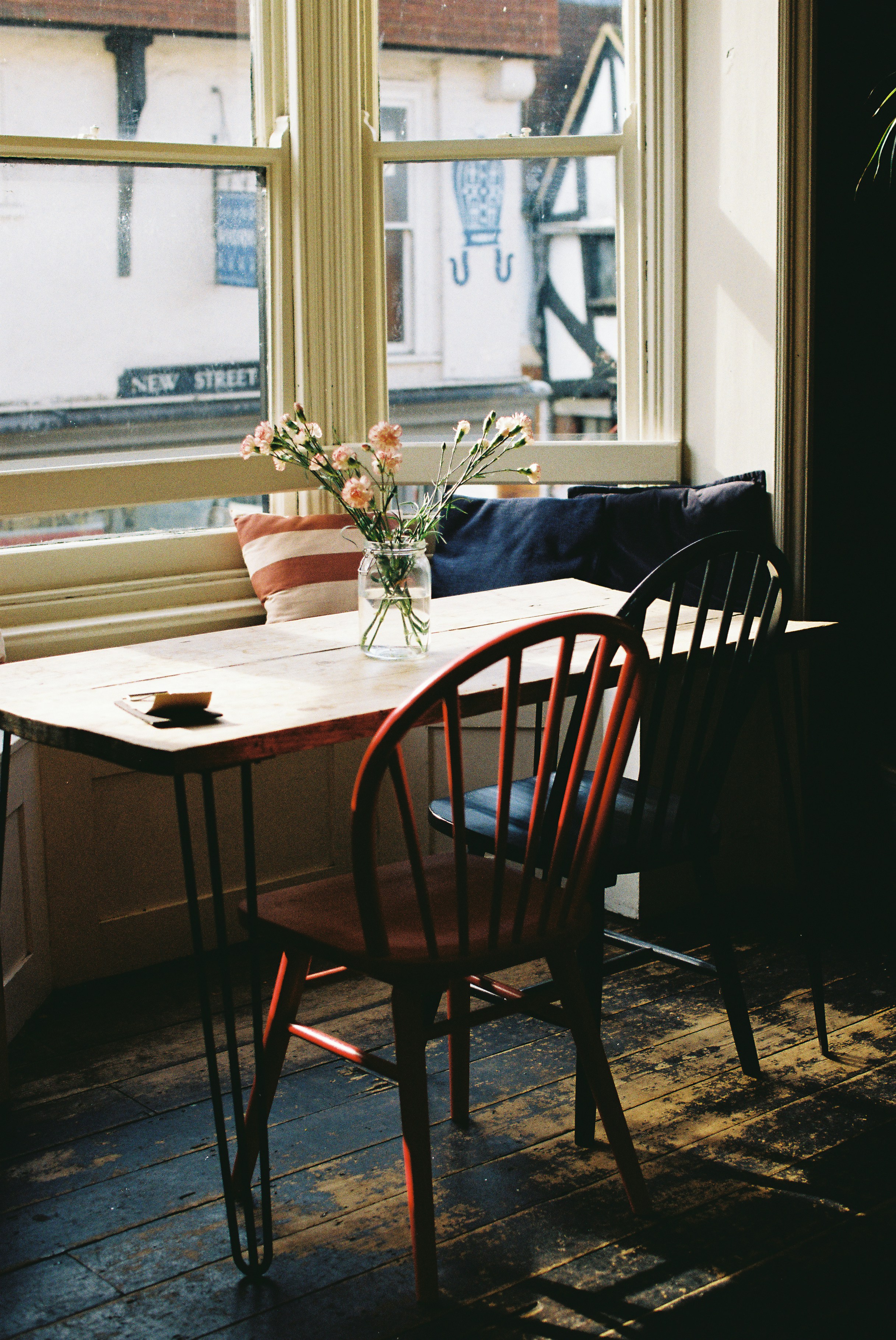 Table and chairs by a sunny window with flowers