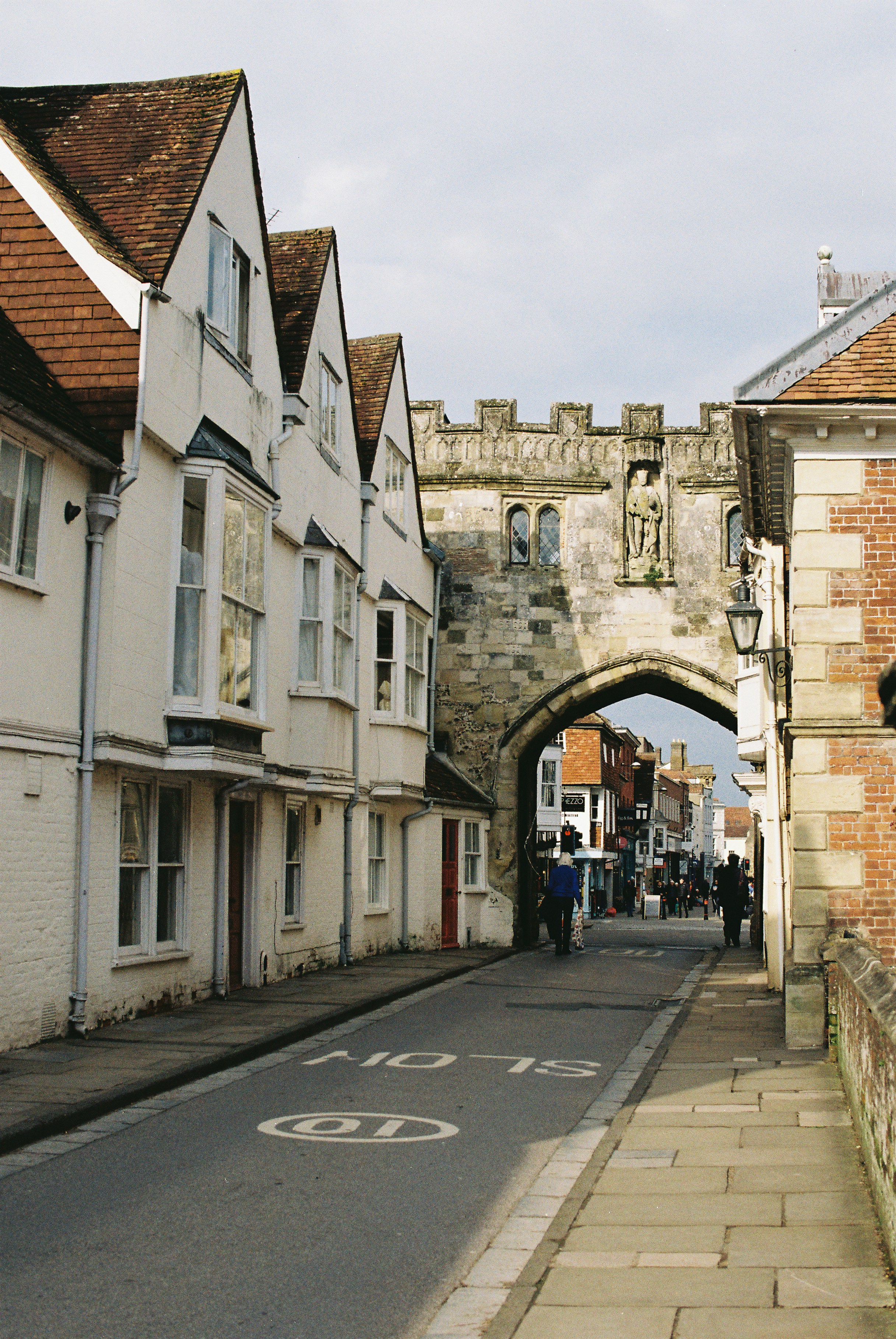 Historischer Torbogen über einer Straße mit Gebäuden.