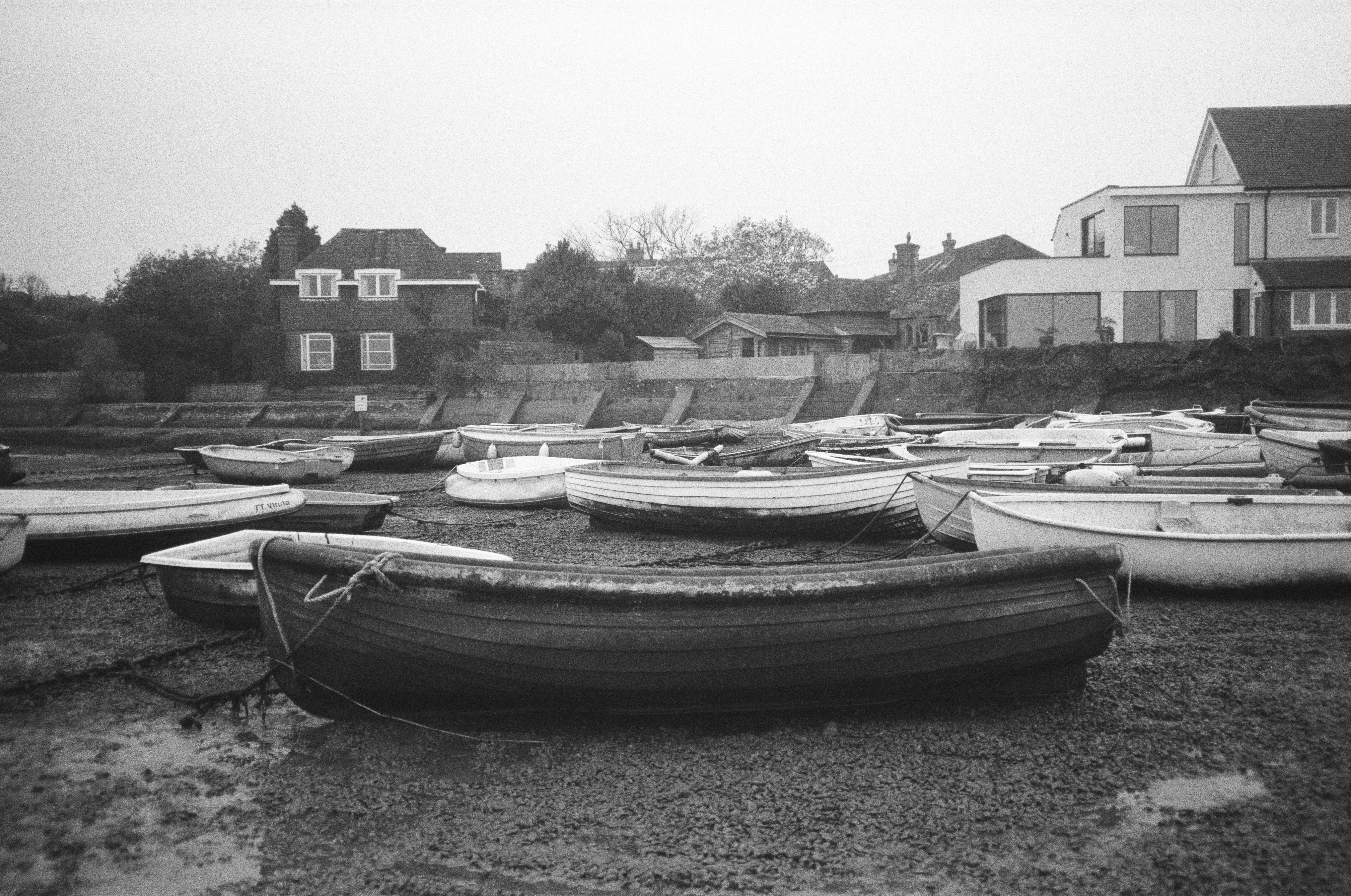 Mehrere Boote ruhen an einem matschigen Ufer.