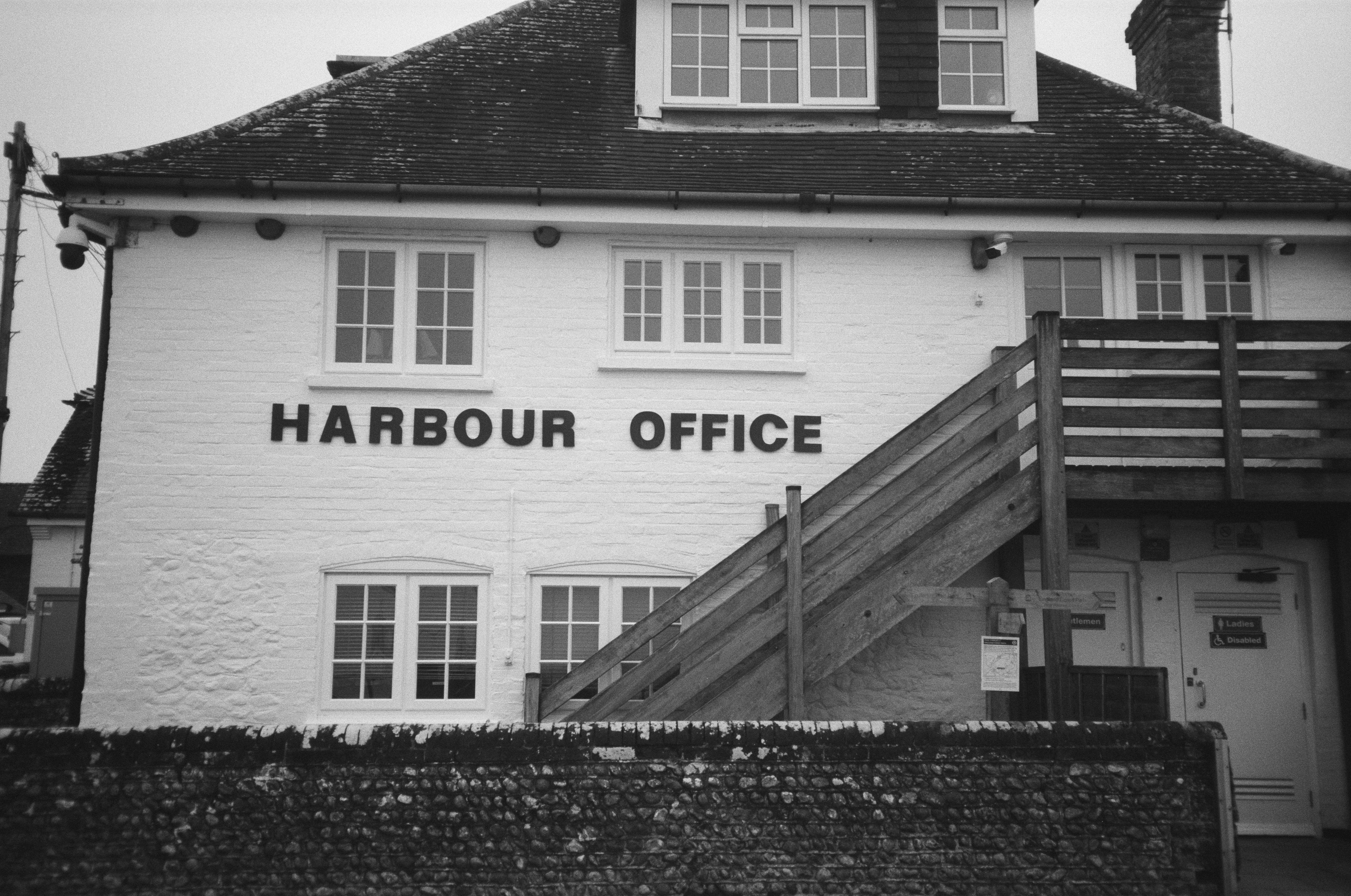 Weißes Gebäude mit "Hafenbüro"-Schild und Holztreppen.