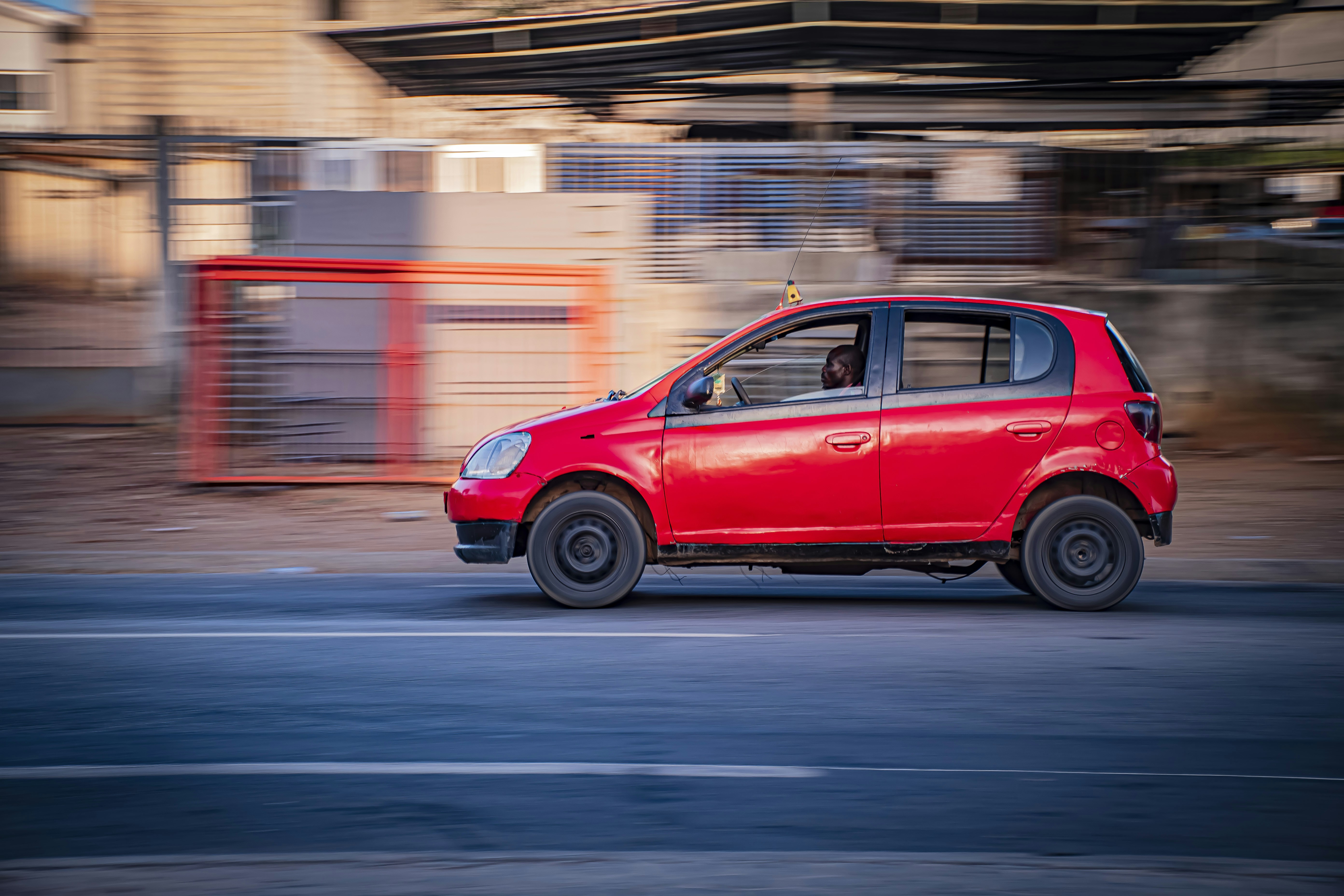 Un coche rojo circulando por una carretera con desenfoque de movimiento