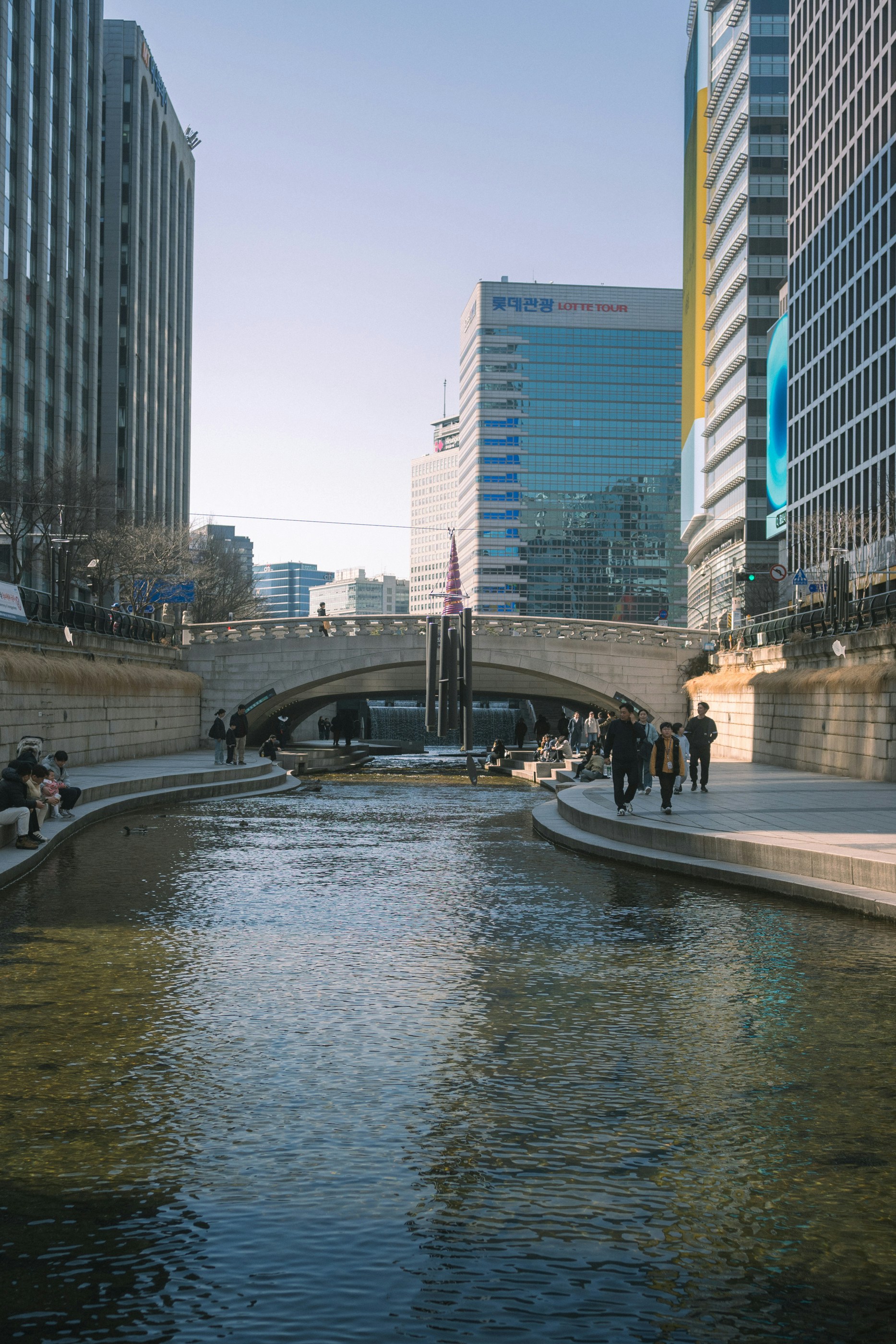 La gente camina junto a un canal entre edificios modernos