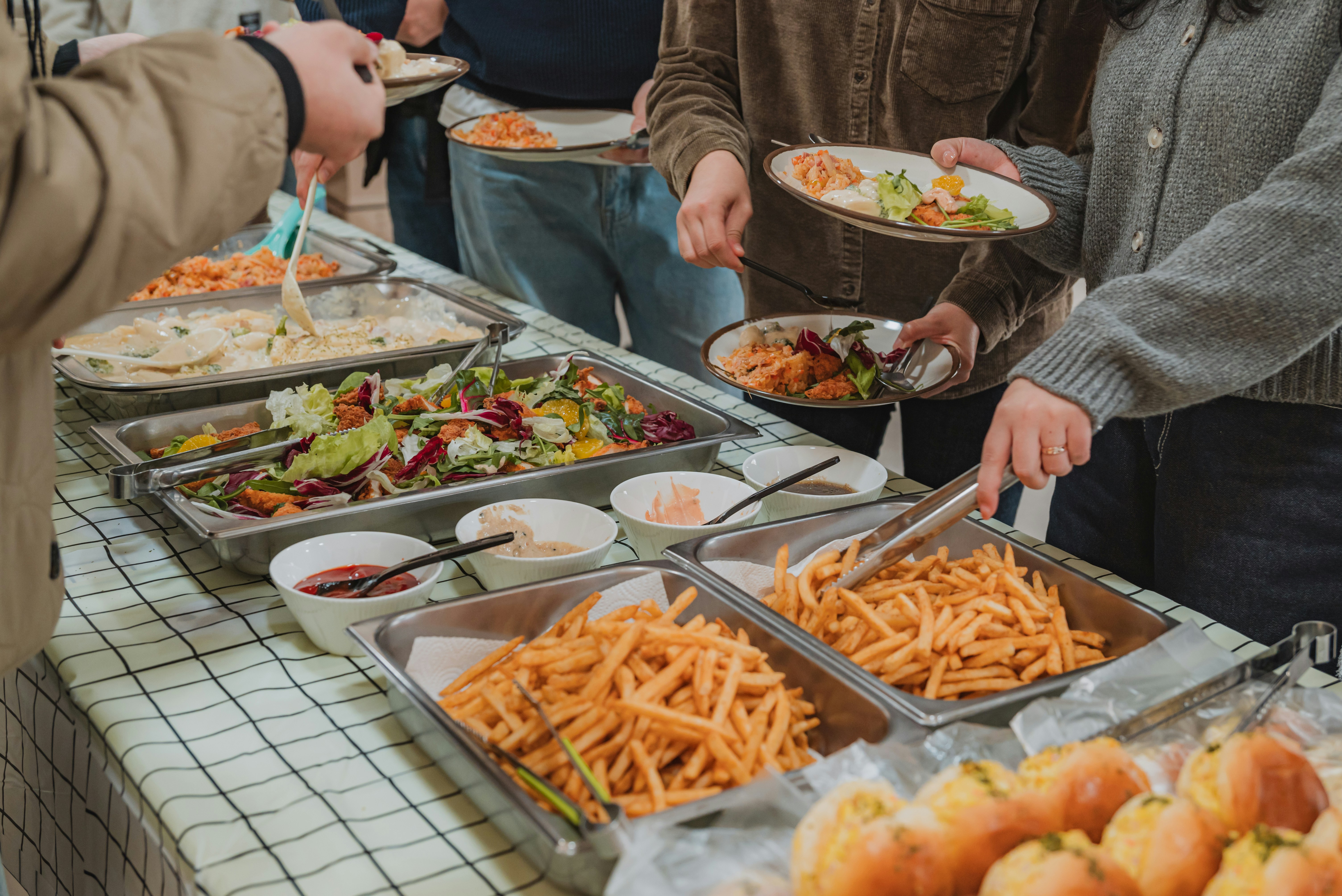 People serving themselves food from a buffet spread.