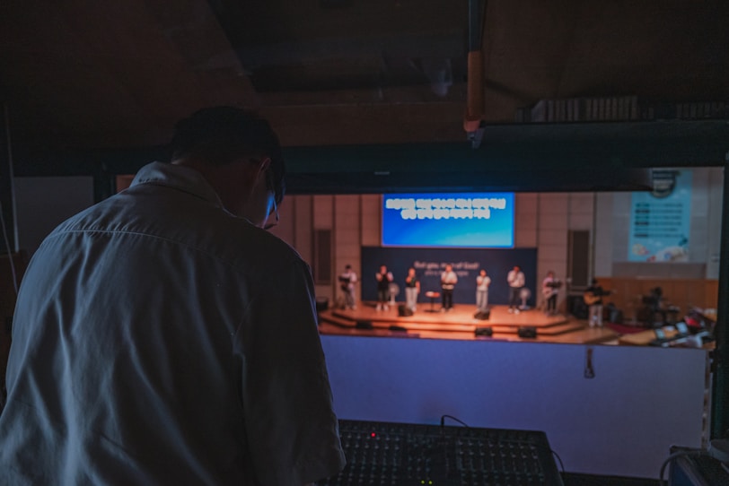Sound technician at mixing board watching performance on stage.