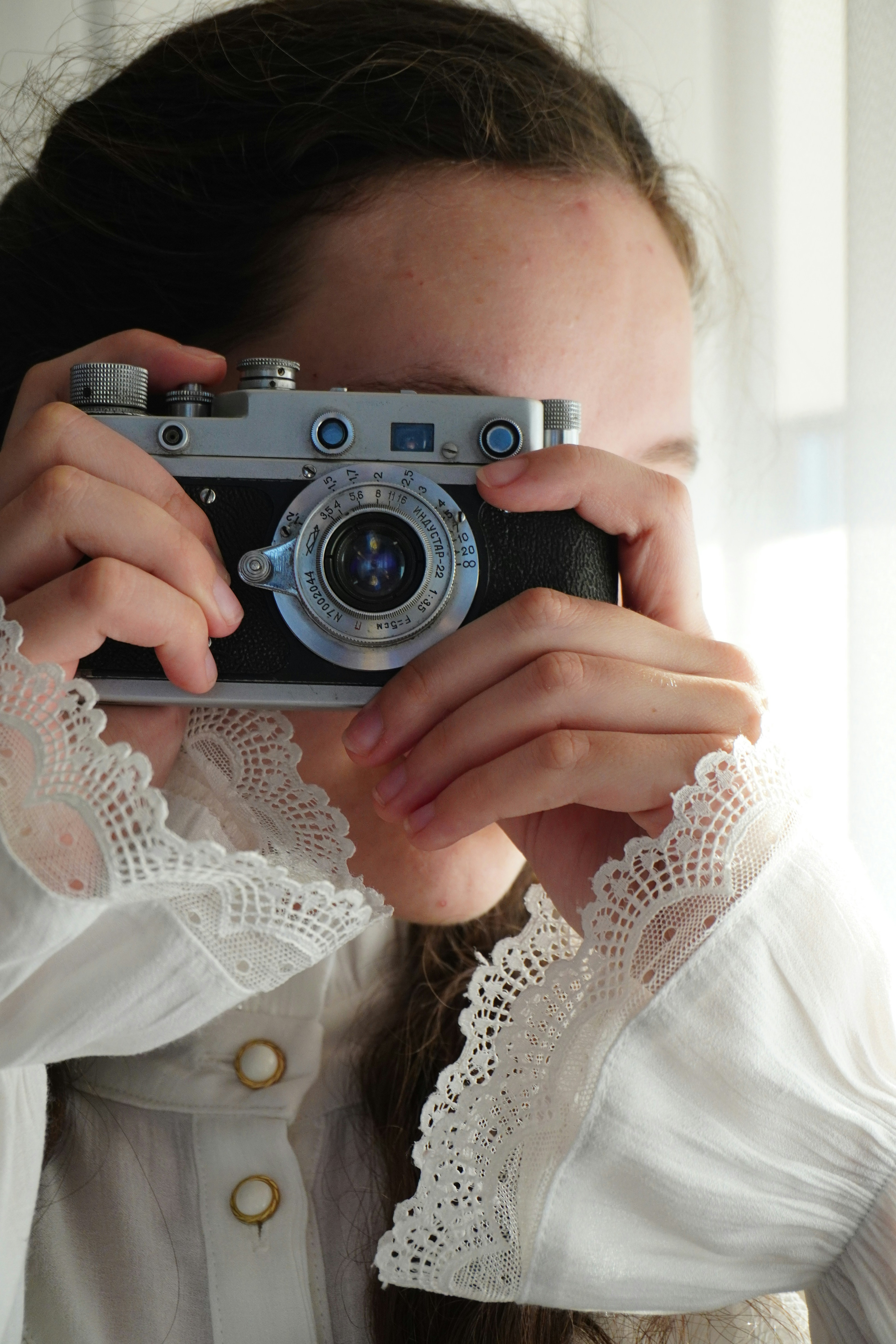 Wanita muda memegang kamera vintage ke matanya