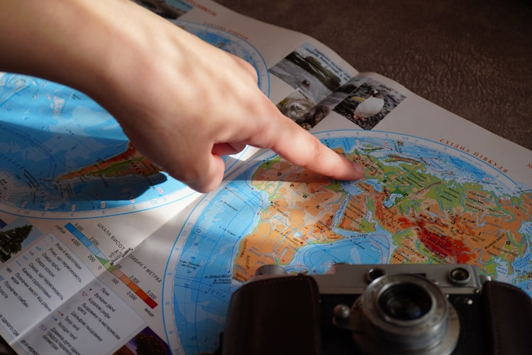 A finger pointing at a location on a world map, representing the strategic decision of choosing international gold storage jurisdictions