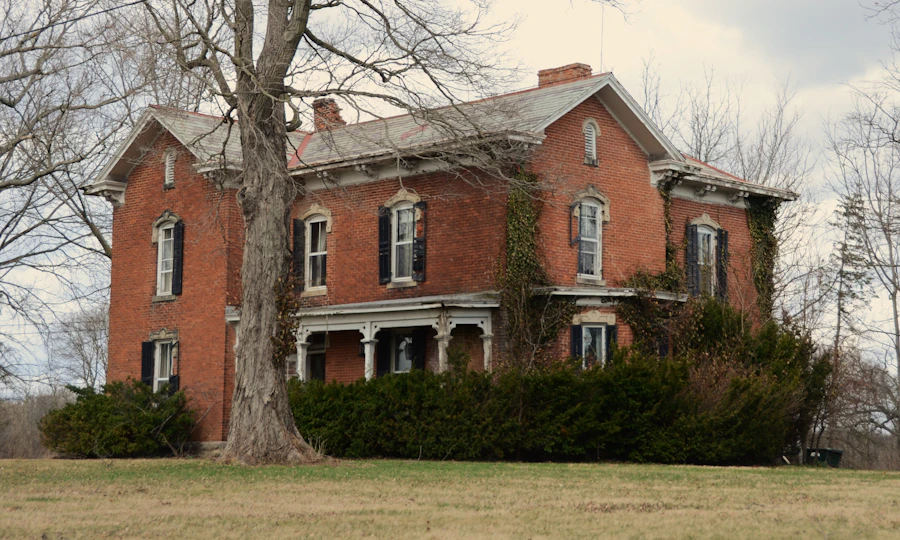 A large red brick house with a front porch behind bare trees