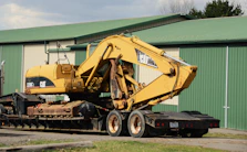 Yellow excavator loaded on a flatbed trailer.