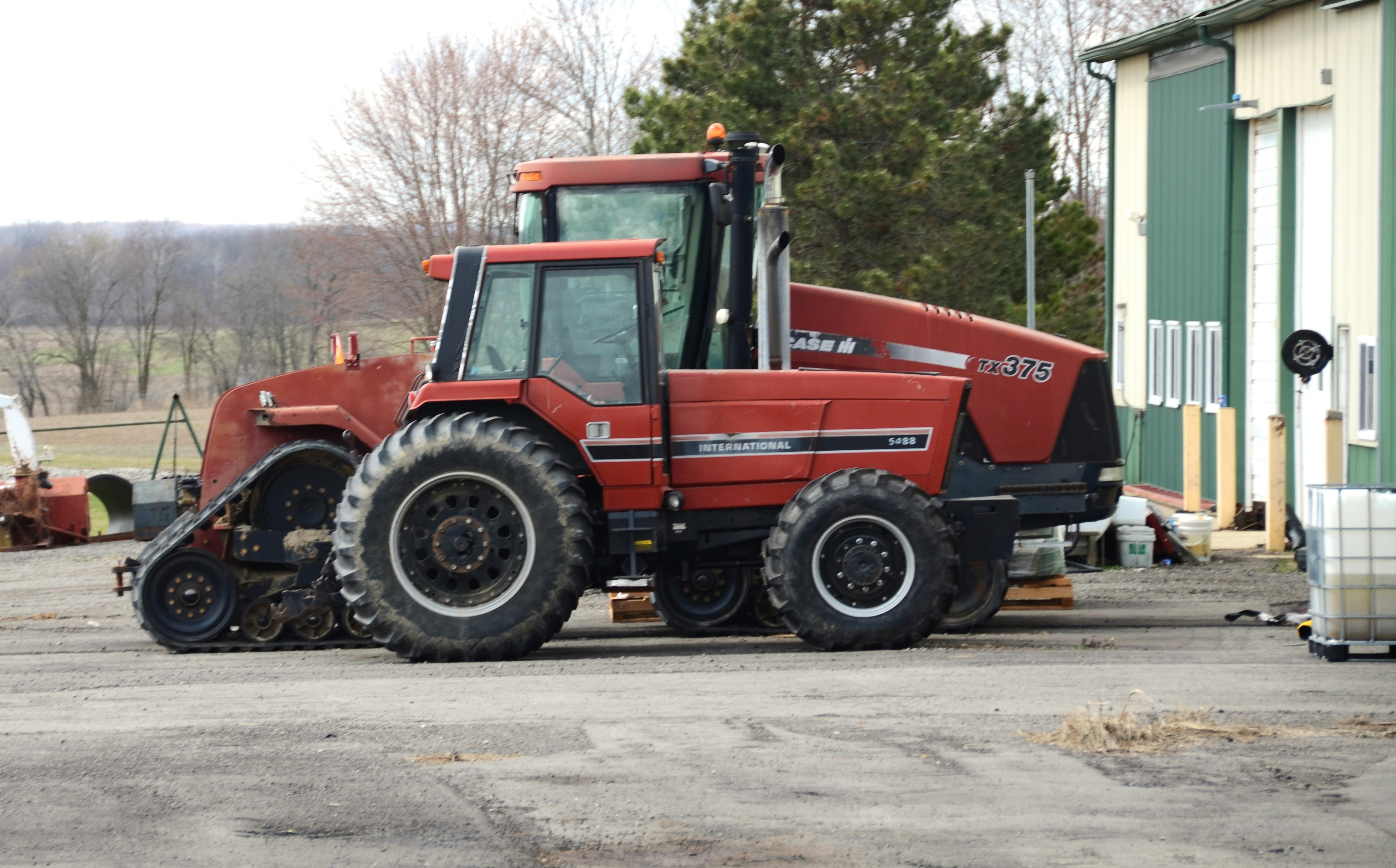 Two red tractors parked outside a building